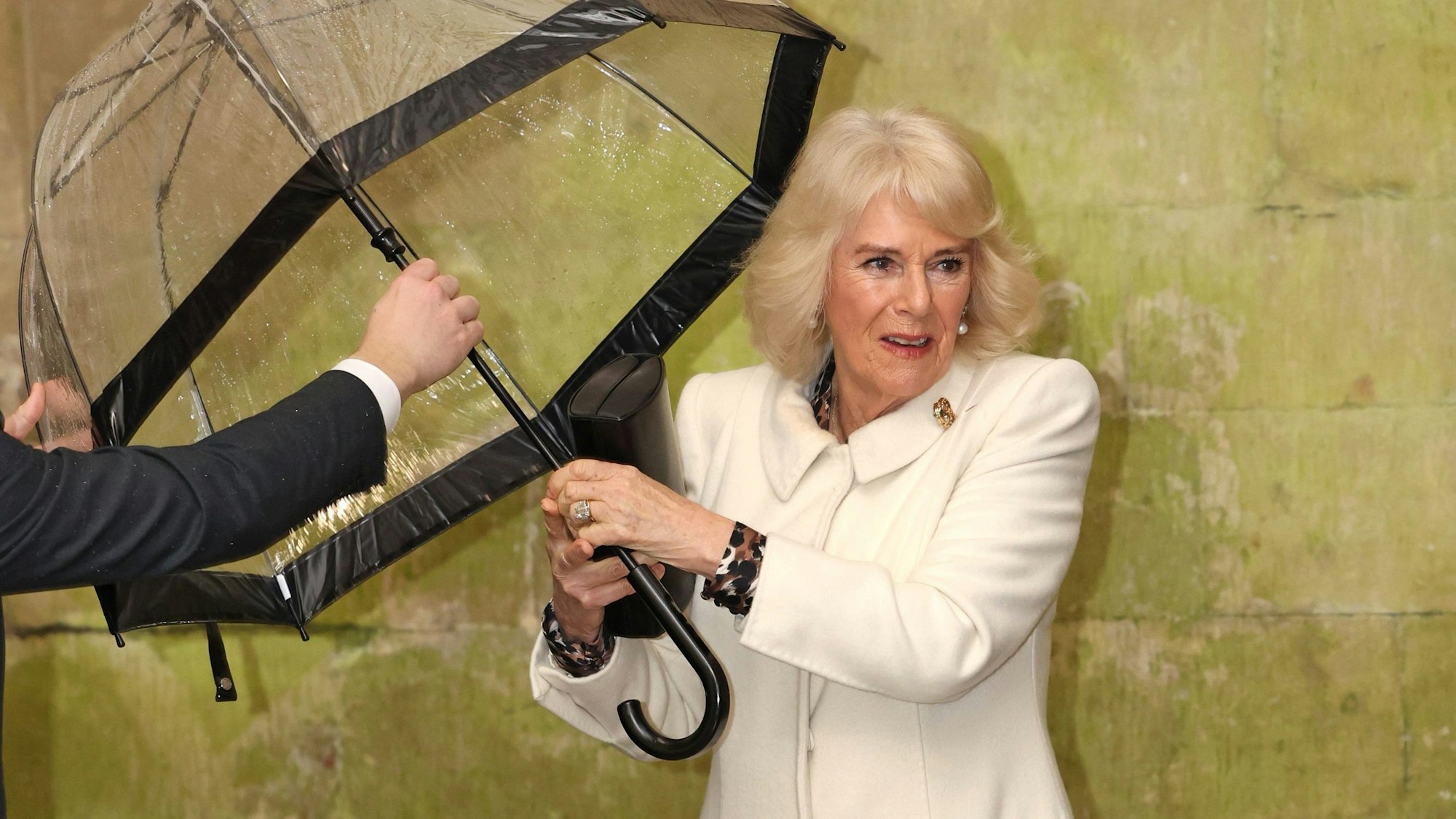 Königin Camilla (m) übergibt einem Helfer ihren Regenschirm, als sie zu einem musikalischen Abend in der Kathedrale von Salisbury in Wiltshire eintrifft.