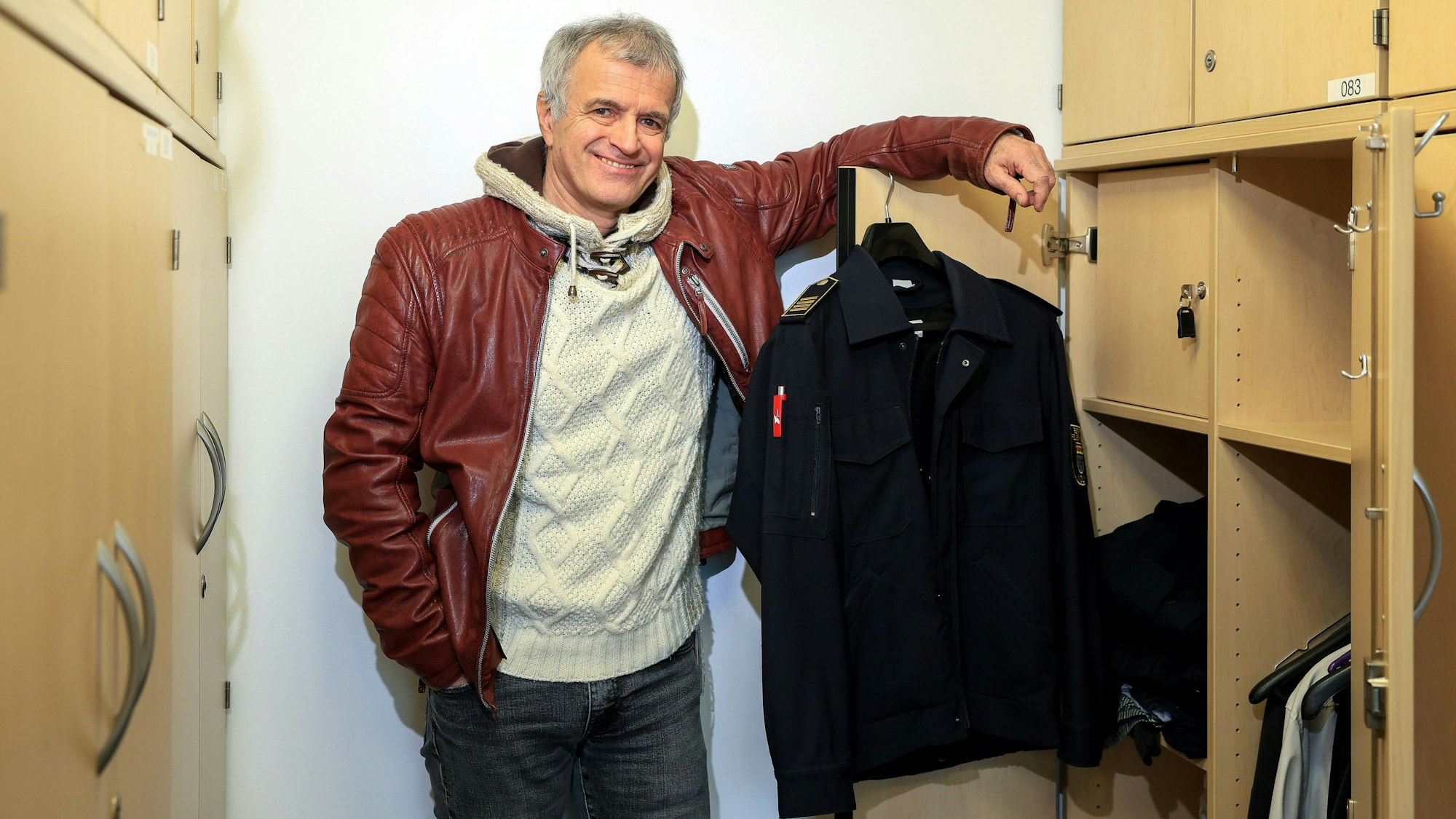 Volker Ruster steht vor seinem Umkleidespind in der Hauptwache der Feuerwehr in Weidenpesch, an einem Haken hängt seine Uniformjacke.