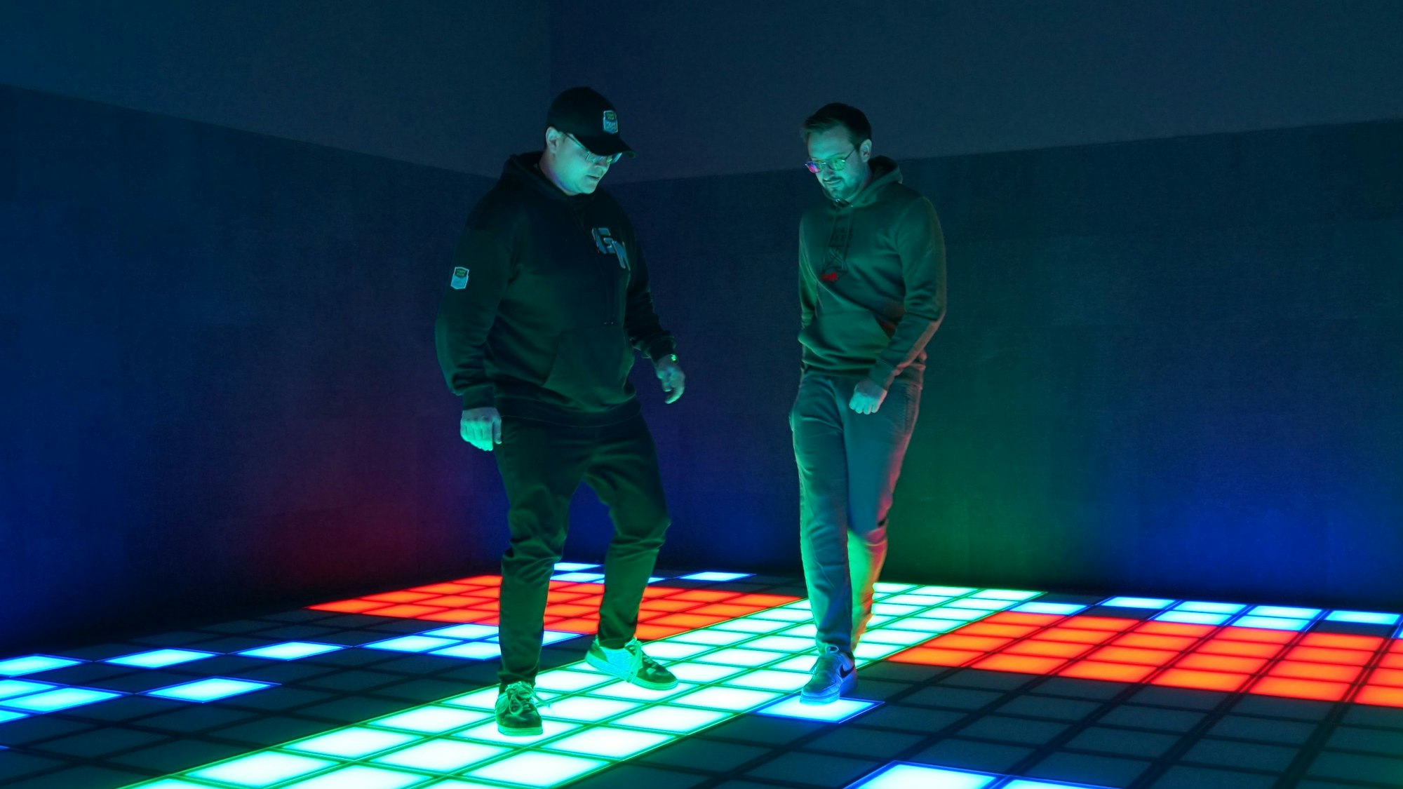 Pierre Pieroth und Paul Nitschke hüpfen auf grünen, roten und blauen LED-Kacheln hin und her.