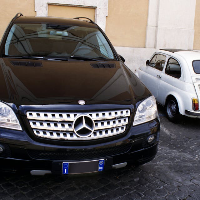 Parkende Autos: Ein großer schwarzer SUV und ein winziger weißer Fiat 500 nebeneinander eingeparkt.&nbsp;
