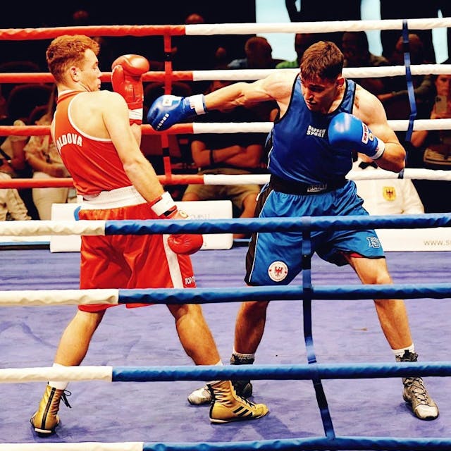 Jason Zeller in Blau boxt gegen einen Gegner in Rot.