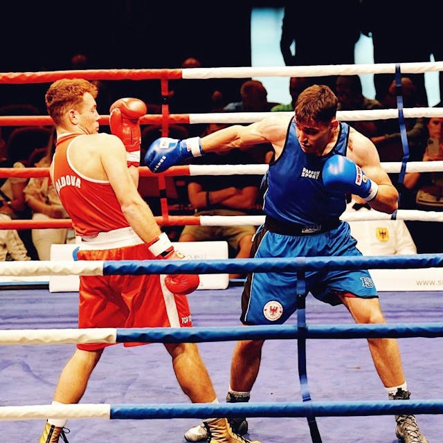 Jason Zeller in Blau boxt gegen einen Gegner in Rot.