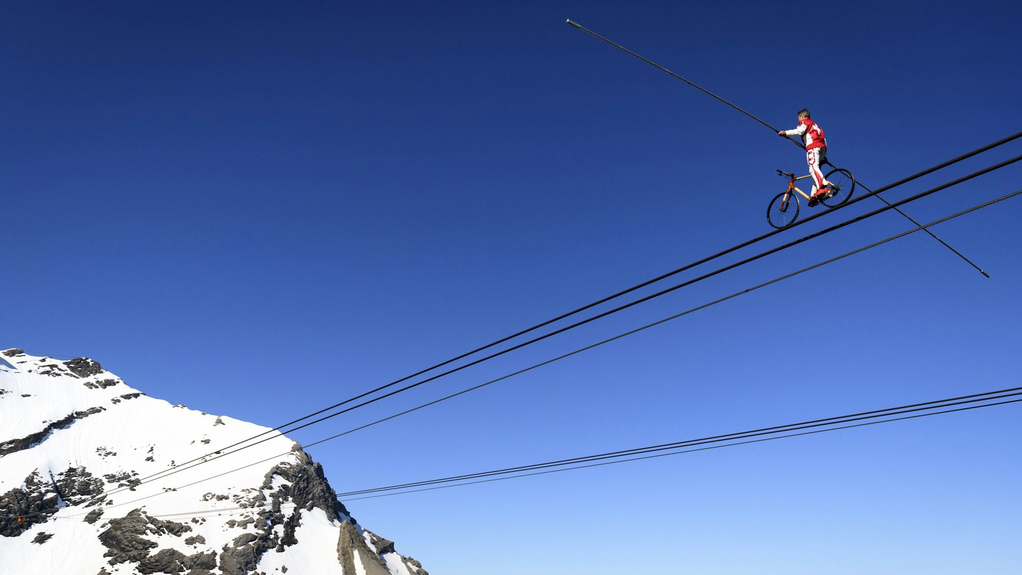 Der Schweizer Drahtseilkünstler Freddy Nock fährt mit einem Fahrrad auf einem Seil einer Sei.