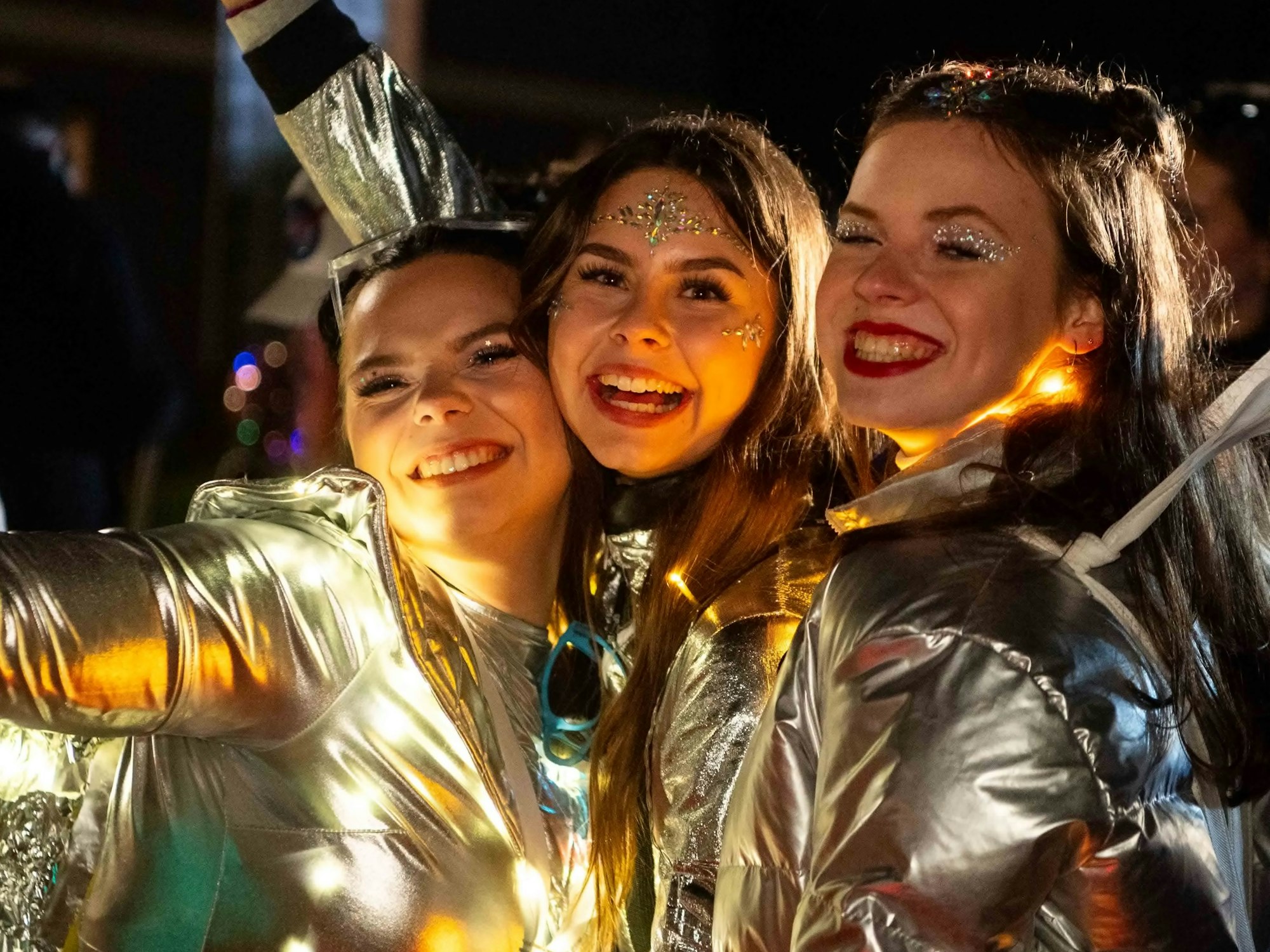 Drei als Astronautinnen verkleidete Karnevalistinnen feiern im Lichterzug in Eiserfey.
