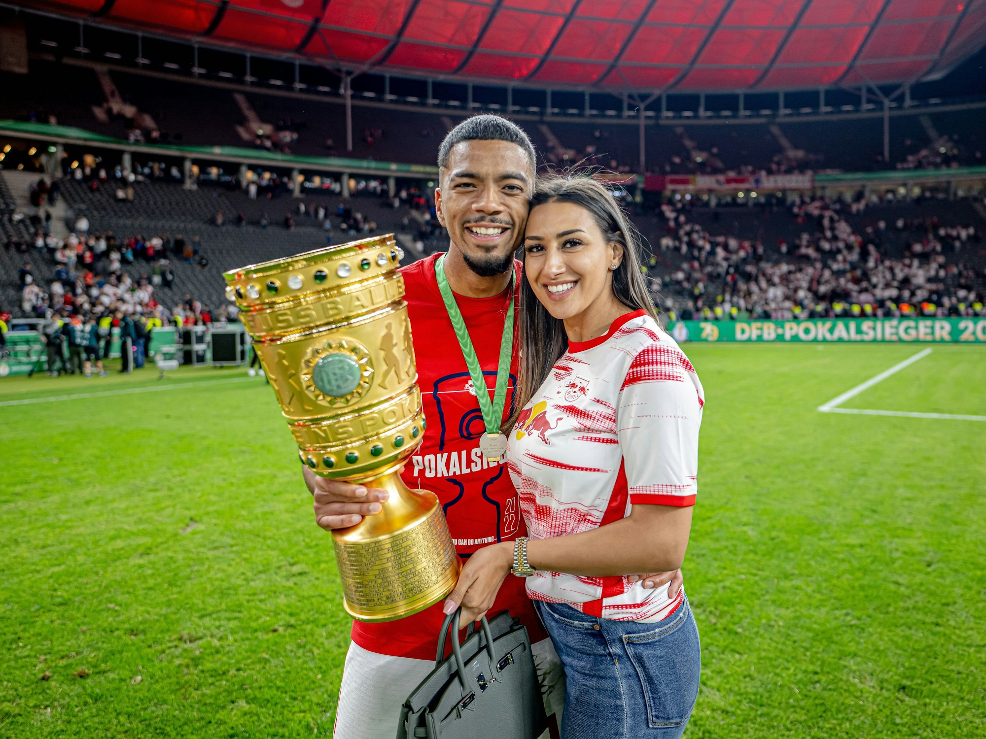 Benjamin Henrichs und seine Freundin Luana machen ein Foto mit dem DFB-Pokal.