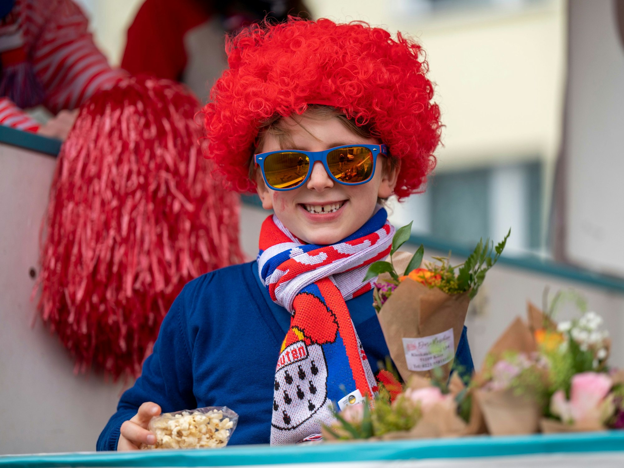 Die gute Laune war den Teilnehmenden beim Karnevalszug im Merheimer Veedel am 10. Februar anzusehen. Hier ein Junge auf einem Karnevalswagen, der Strüßje und Popcorn in der Hand hält.