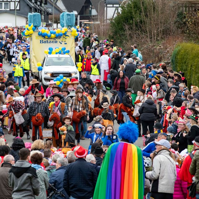 Eine Straße, voll mit Jecken. Ein Karnevalszug zieht durch den Ortskern in Hartegasse in Lindlar.