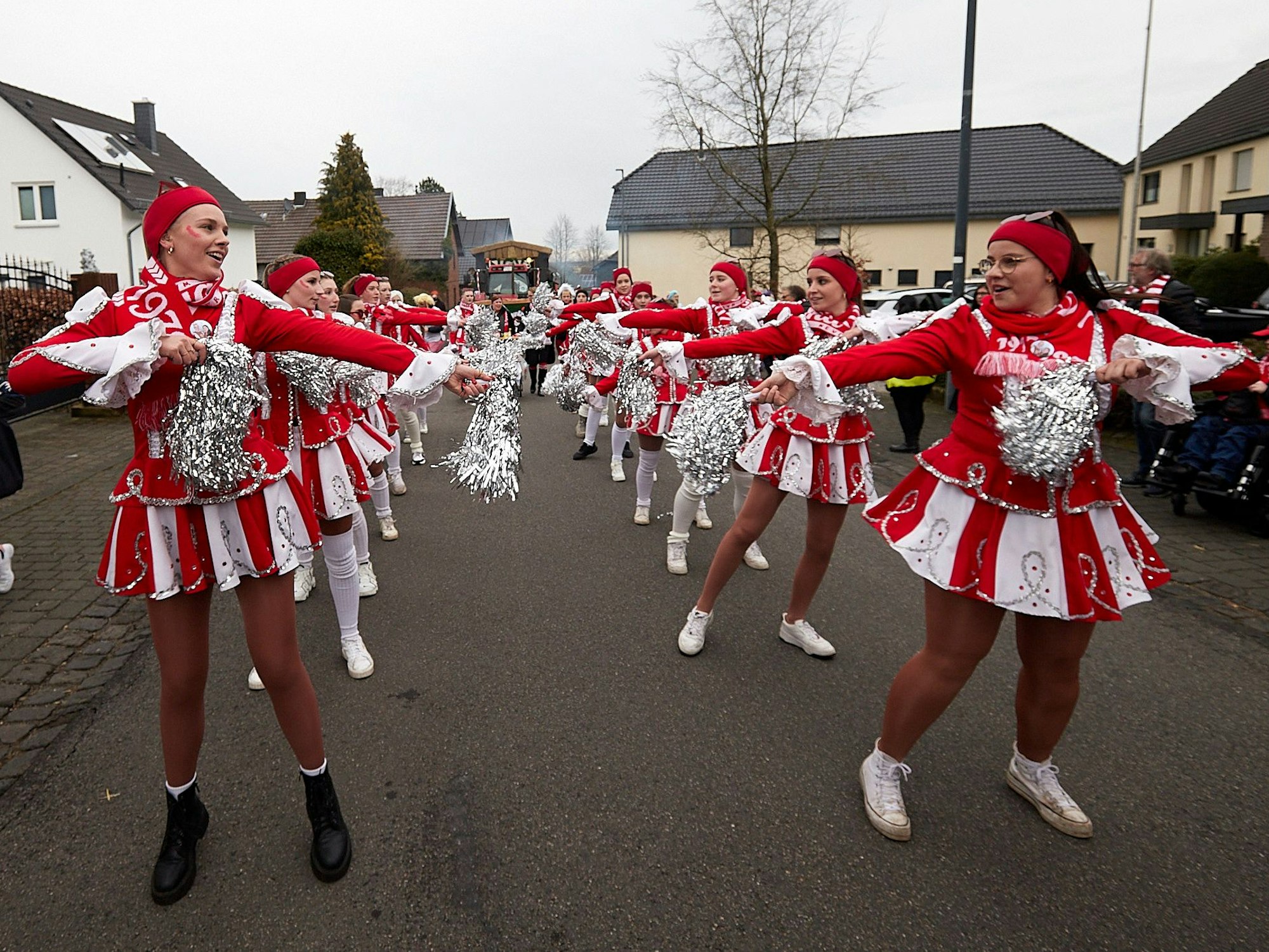 Die Tänzerinnen des Vereinsbunds Dreiborn tanzen in ihren rot-weißen Kostümen auf der Straße. Sie haben silberne Pompoms in den Händen.