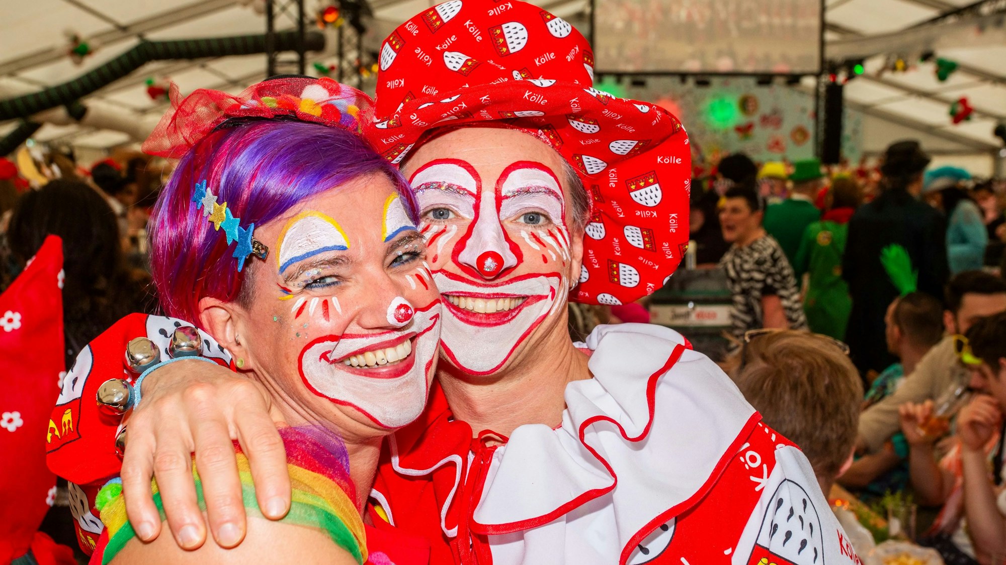 Zwei kostümierte und als Clowns geschminkte Frauen im Festzelt bei einer Prunksitzung.
