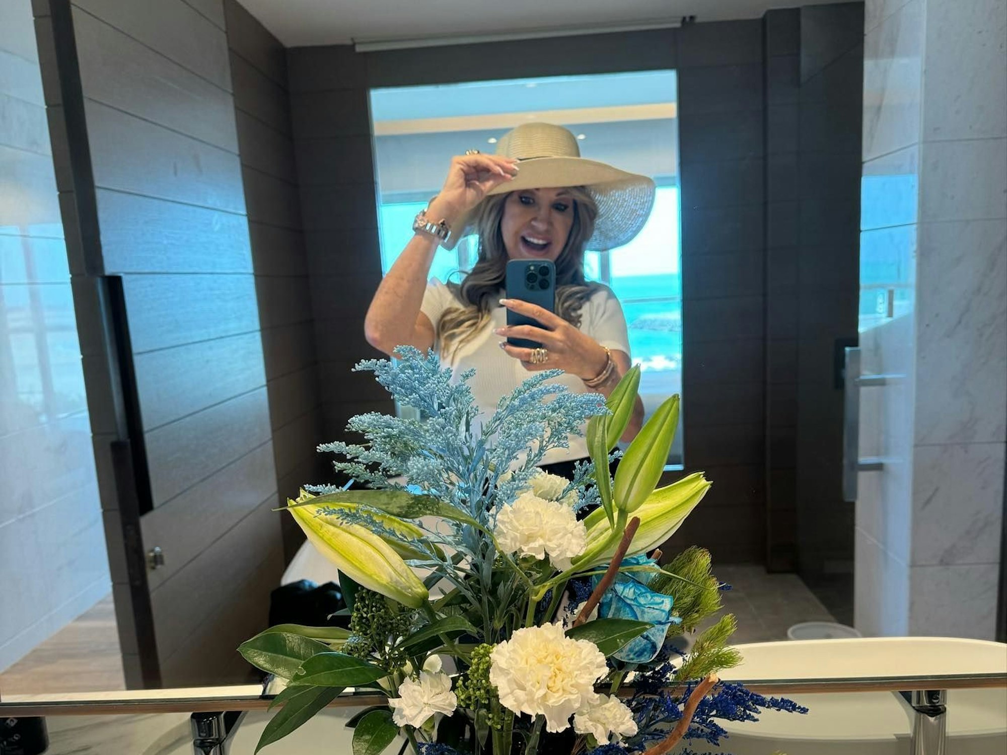 Carmen Geiss steht vor einem Spiegel und macht ein Selfie. Sie trägt einen Hut und lächelt.