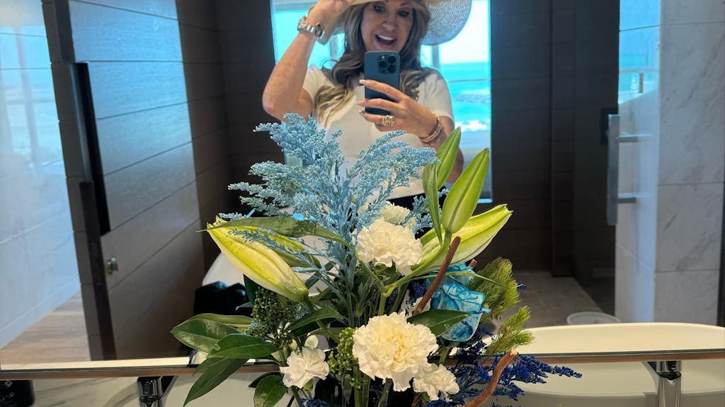 Carmen Geiss steht vor einem Spiegel und macht ein Selfie. Sie trägt einen Hut und lächelt.