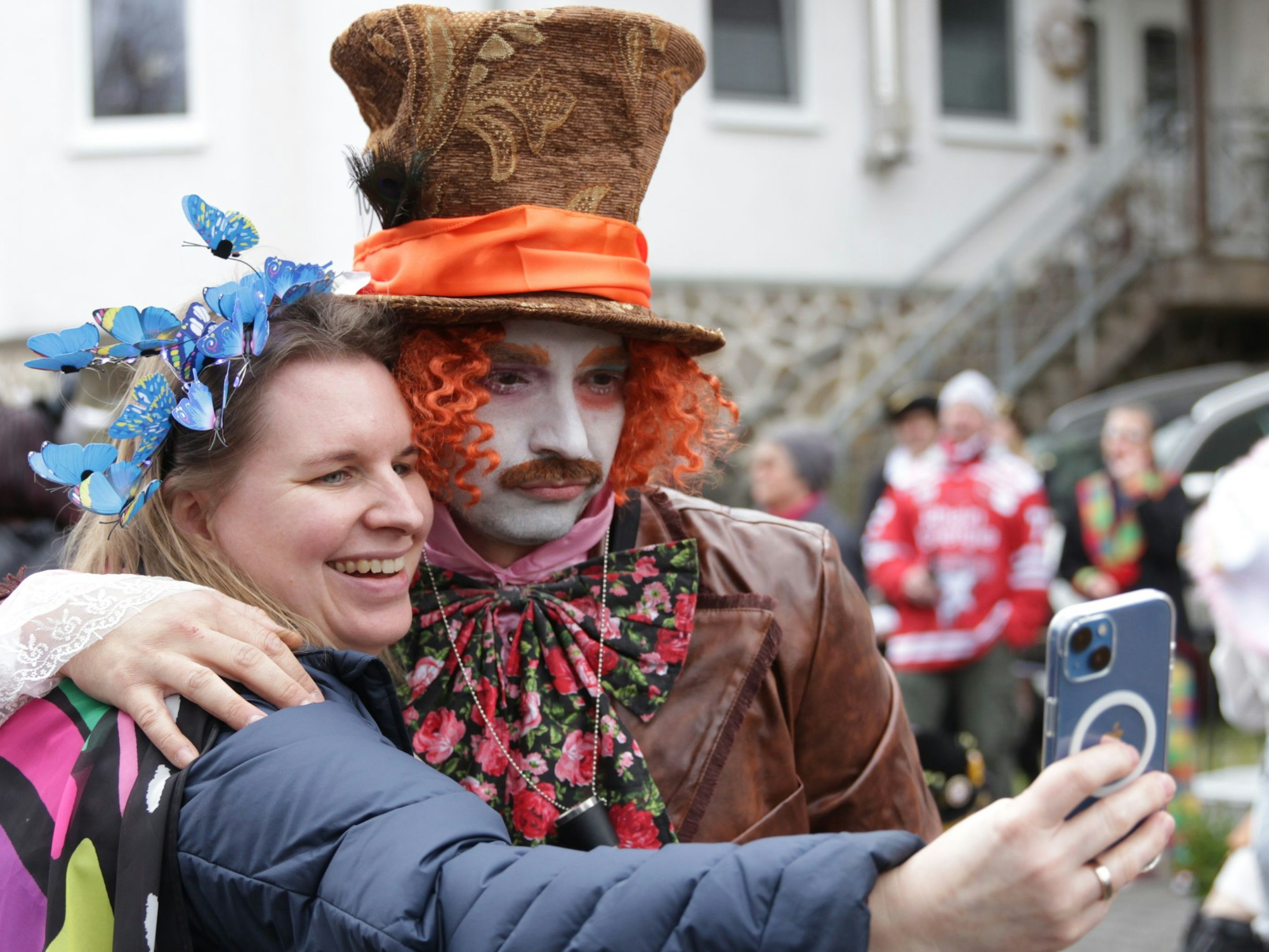 Eine verkleidete Zuschauerin des Vussemer Karnevalszugs macht ein Selfie mit Helmut Sanden, der als verrückter Hutmacher aus Alice im Wunderland kostümiert und geschminkt ist.
