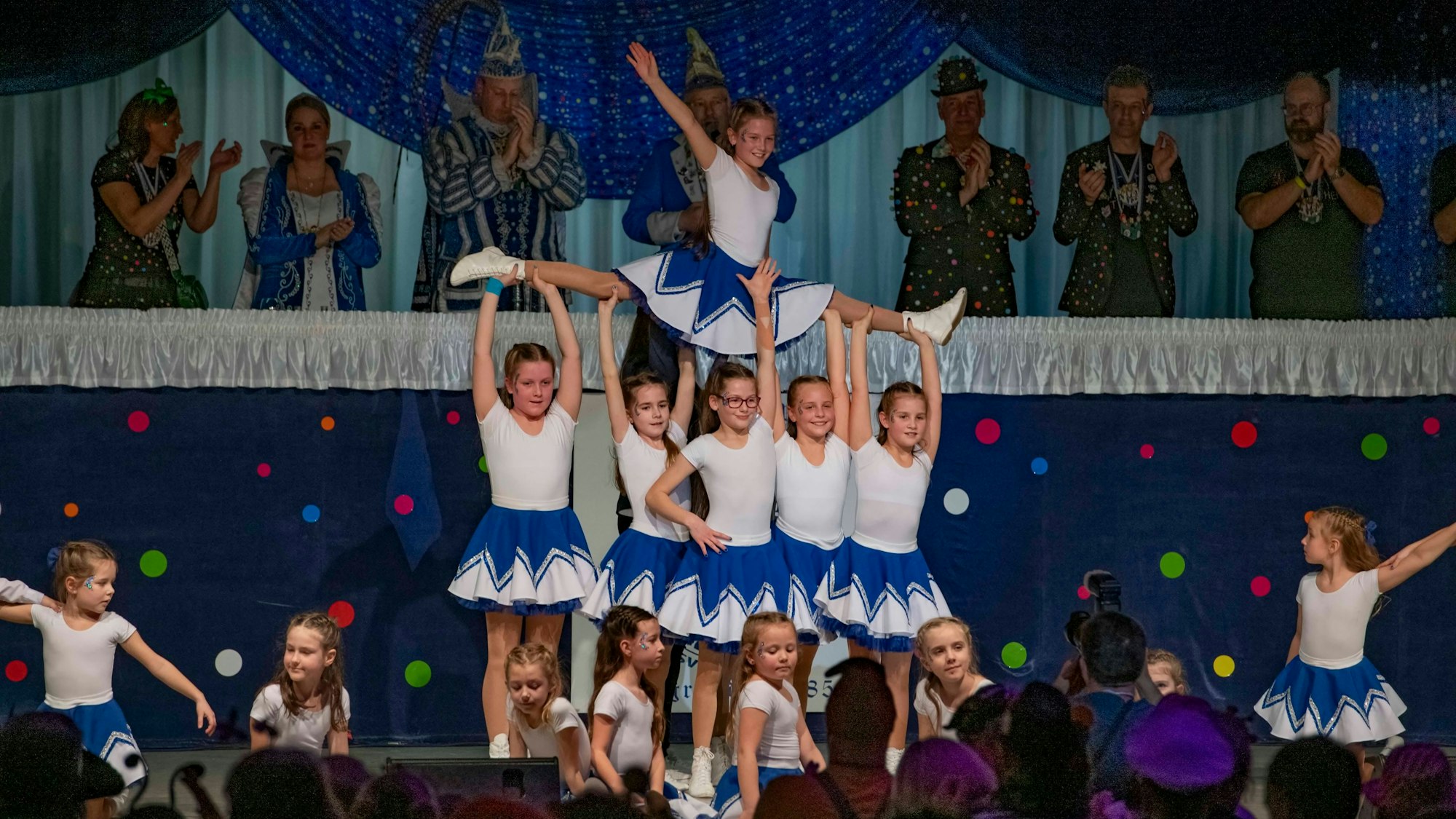 Eine Karnevals-Kindertanzgruppe zeigt eine Choreografie auf der Bühne einer Sitzung.