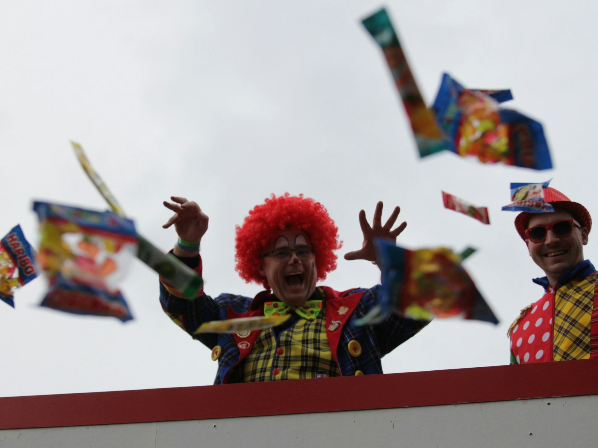 Zwei Clowns schmeißen von einem Wagen Kamelle zu den Zuschauern des Karnevalszugs in Vussem.
