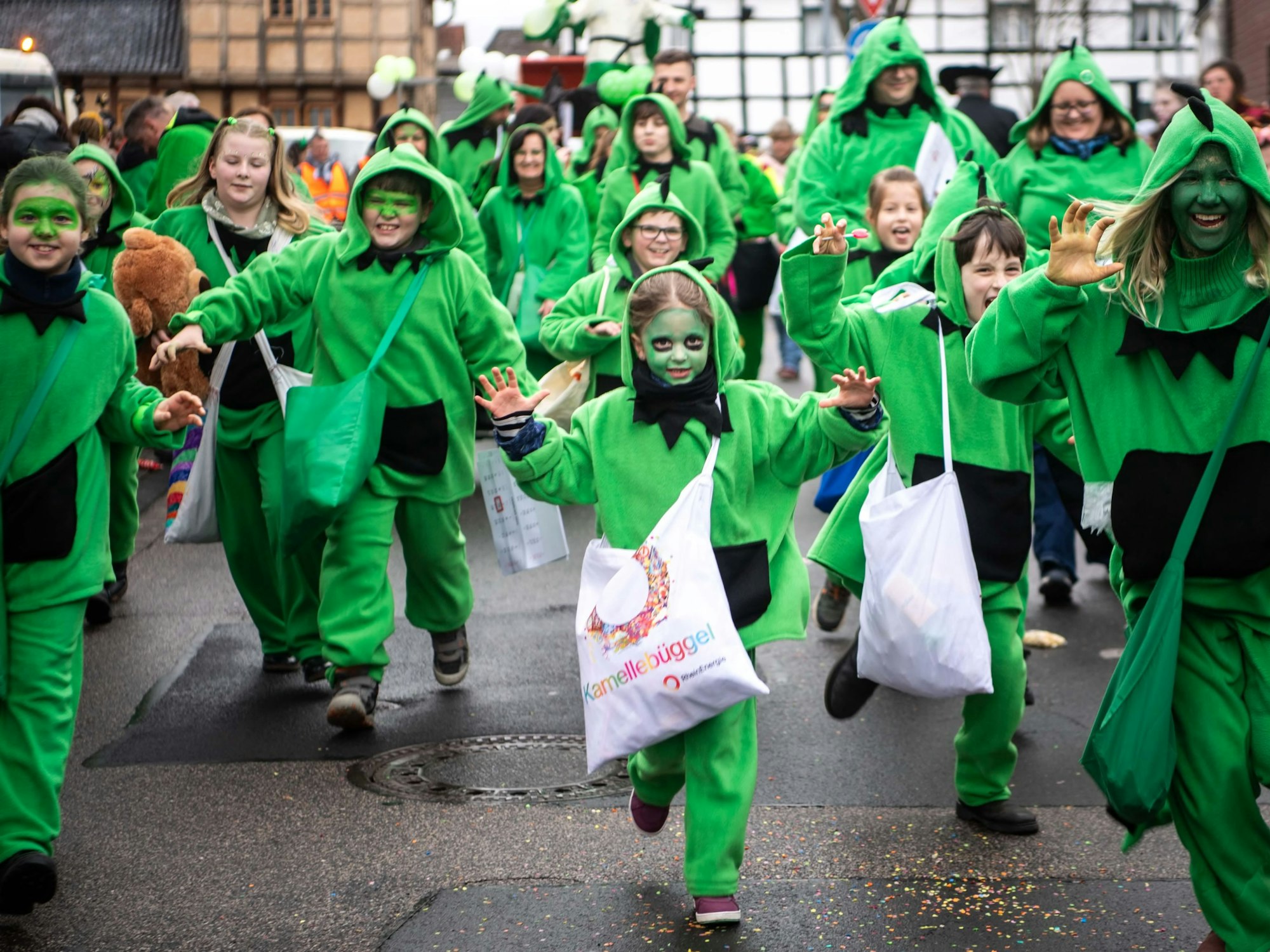 Eine große Gruppe grün verkleideter Drachen vom Teakwondo-Club „Fair Dragon“ rennt in Kuchenheim durch die Straßen.