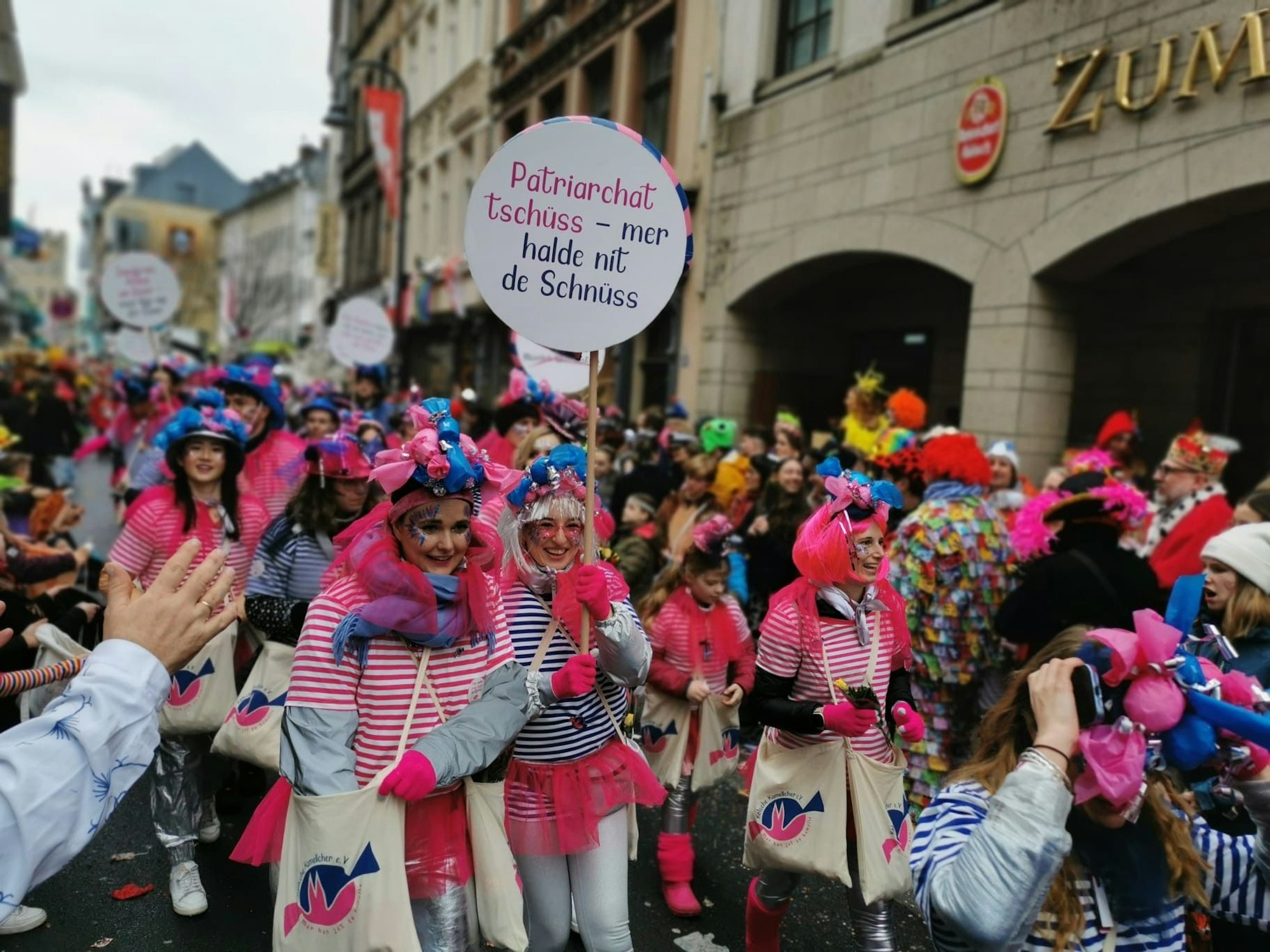 Frauen in Kostümen mit pinken Haaren und rosa Röcken.