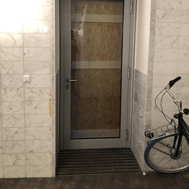 Eine Glastür, die von außen mit einer Spanplatte verbarrikadiert ist.