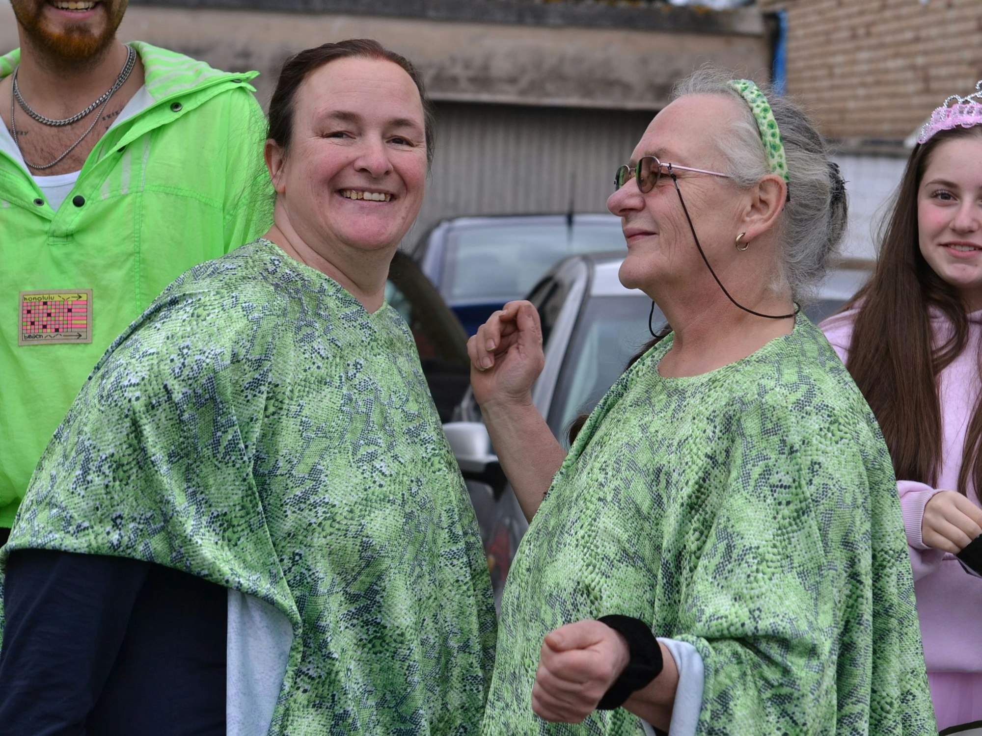 Freudestrahlend genossen die Mülheim/Wichtericher Jecken ihren Straßenkarneval. Zwei Frauen tragen grüne Umhänge und lachen.