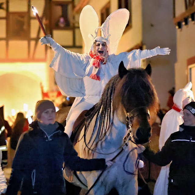 Als weißer Geist verkleidet und mit Flügeln auf dem Rücken reitet Blankenheims Prinzessin Dilek I. (Schröder-Tas) an der Spitze des Geisterzugs. Ihr Pferd wird von zwei Helferinnen geführt.