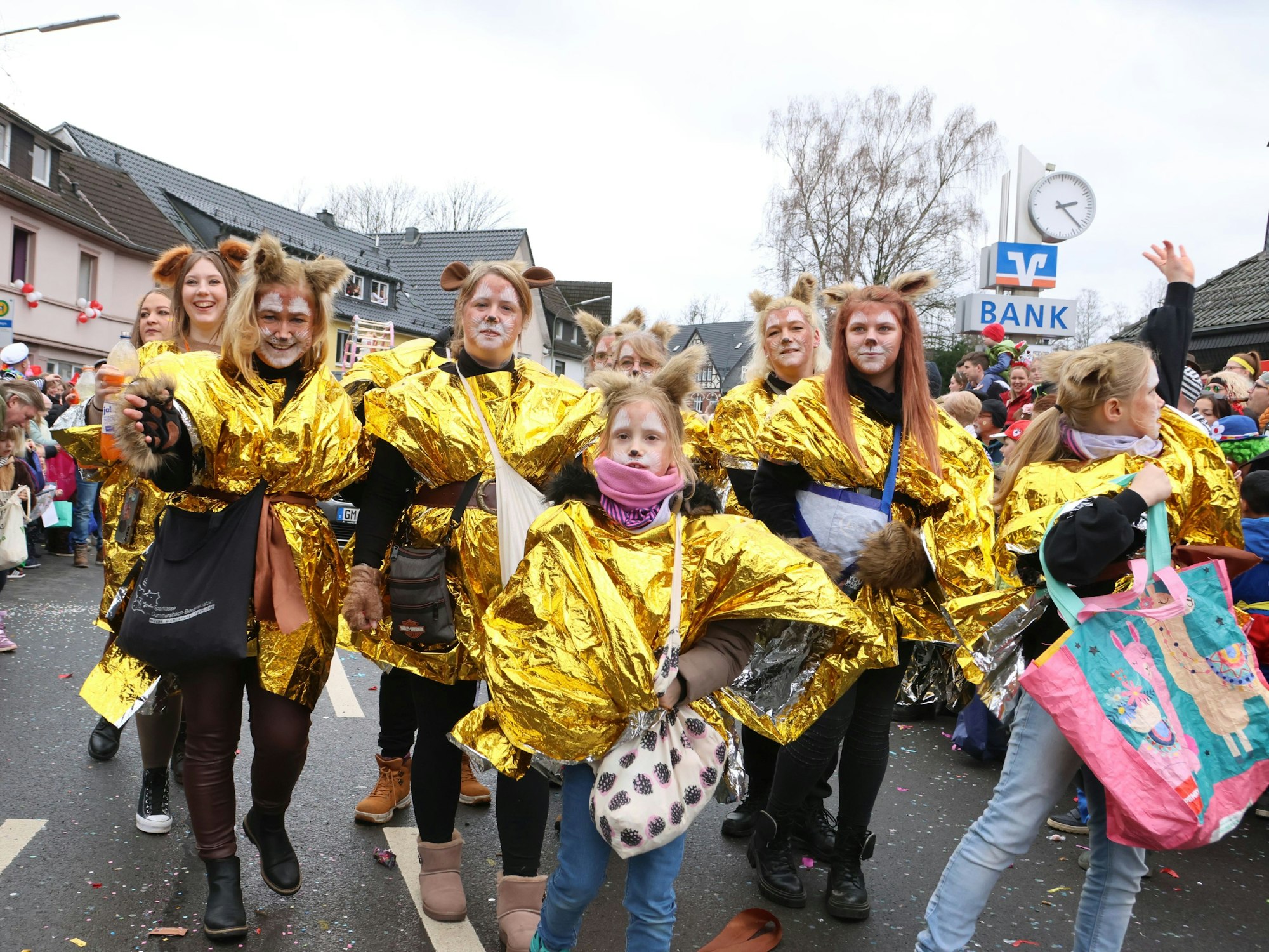 Eine Gruppe eines Karnevalszuges trägt goldene Umhänge.