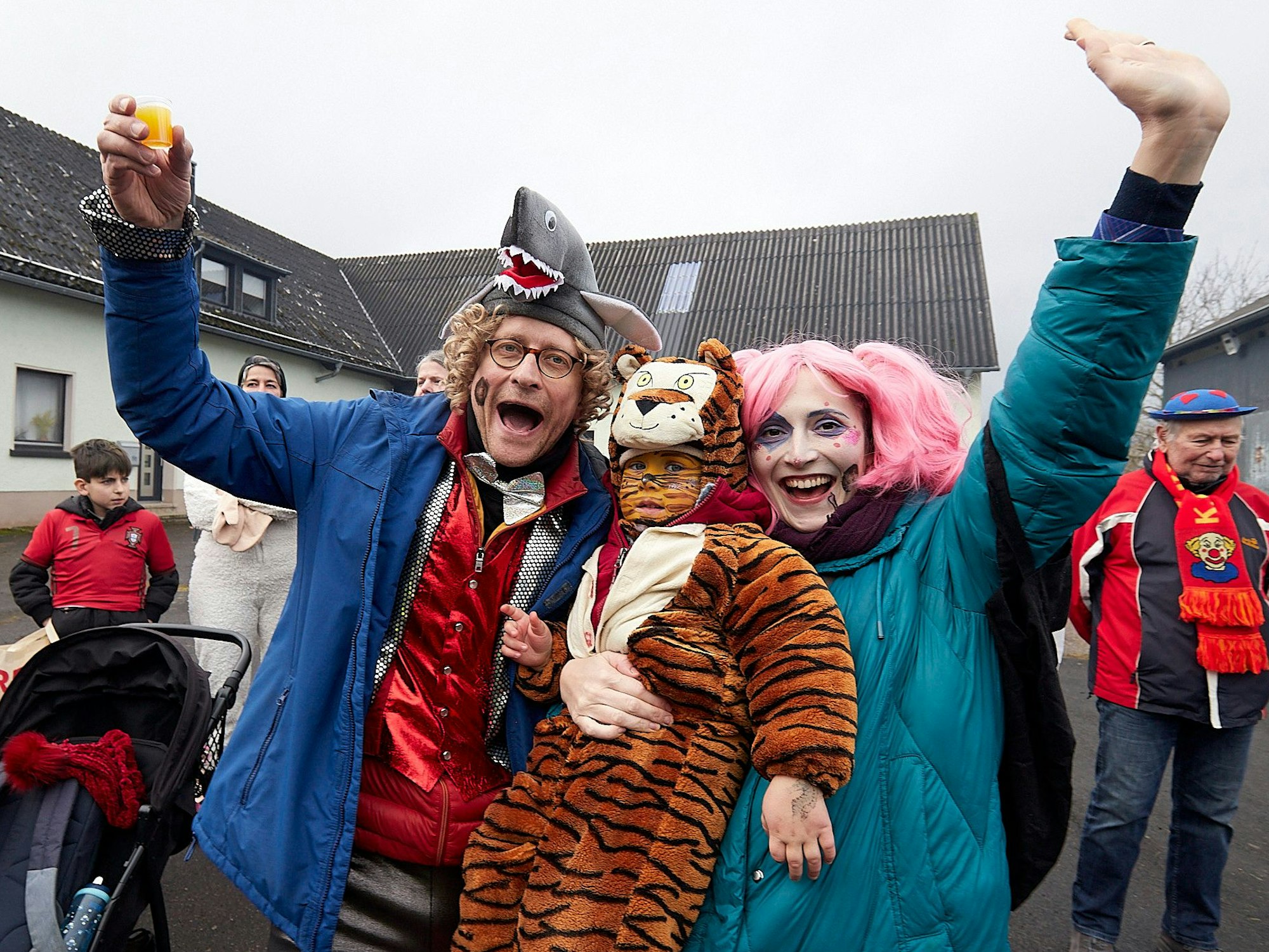 Drei verkleidete Karnevalisten genießen den am Wegesrand den Zoch in Udenbreth.