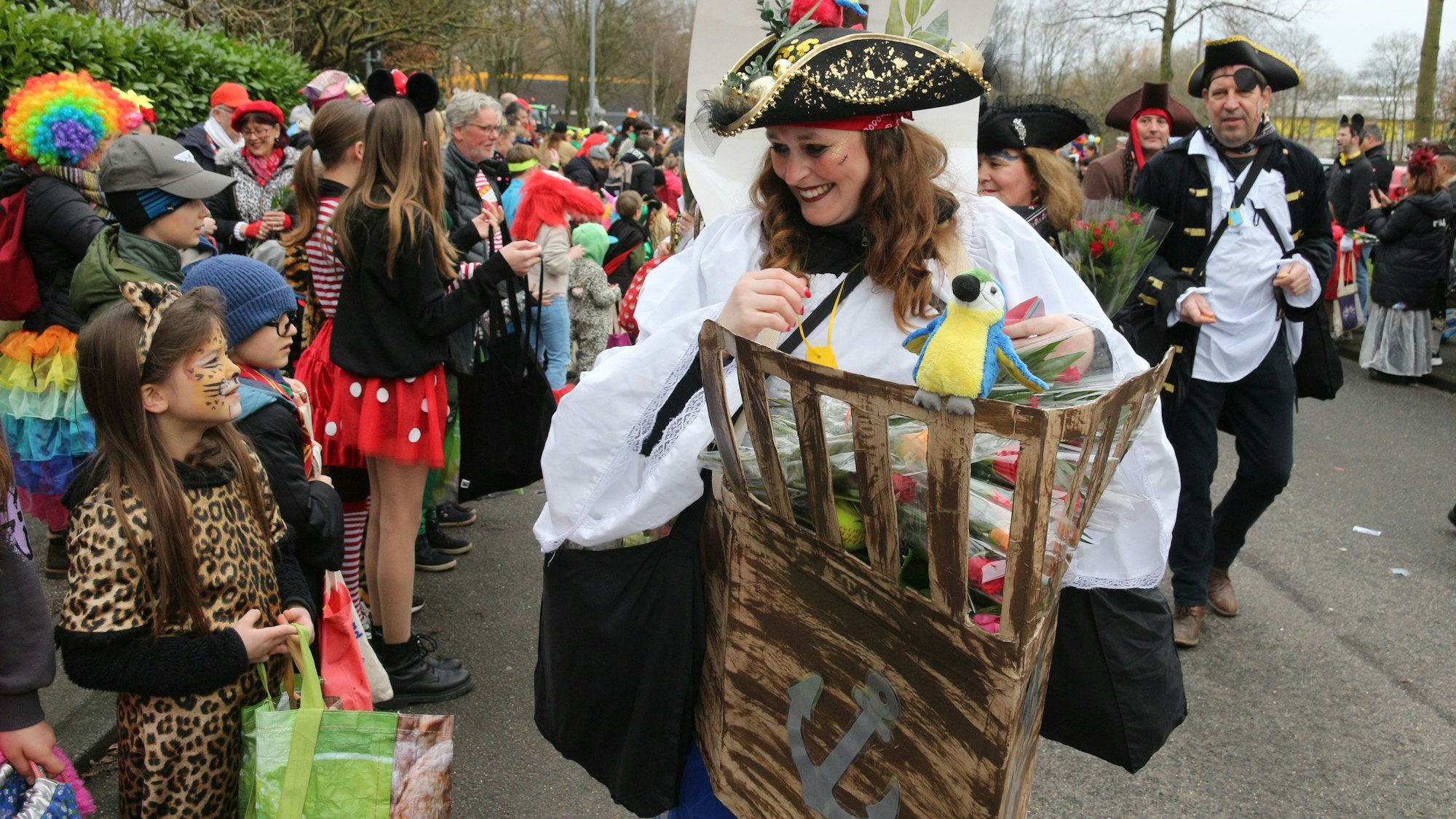 Auf dem Foto sind die Piraten der Brauweiler Pänz zu sehen. Sie verteilen Wurfmaterial an Kinder am Straßenrand.