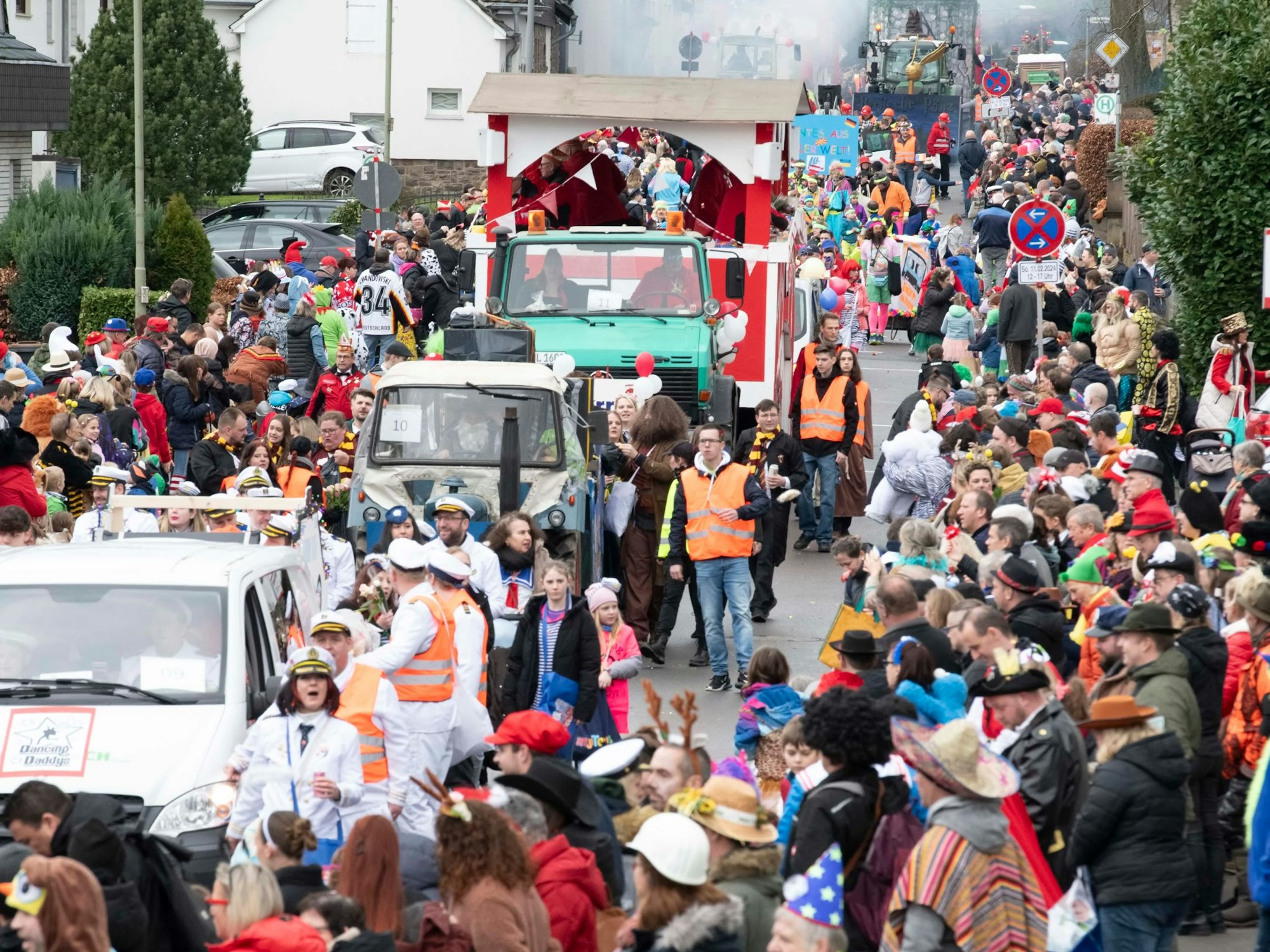 Ein Karnevalszug schlängelt sich durch eine mit Jecken voll besetzte Straße.