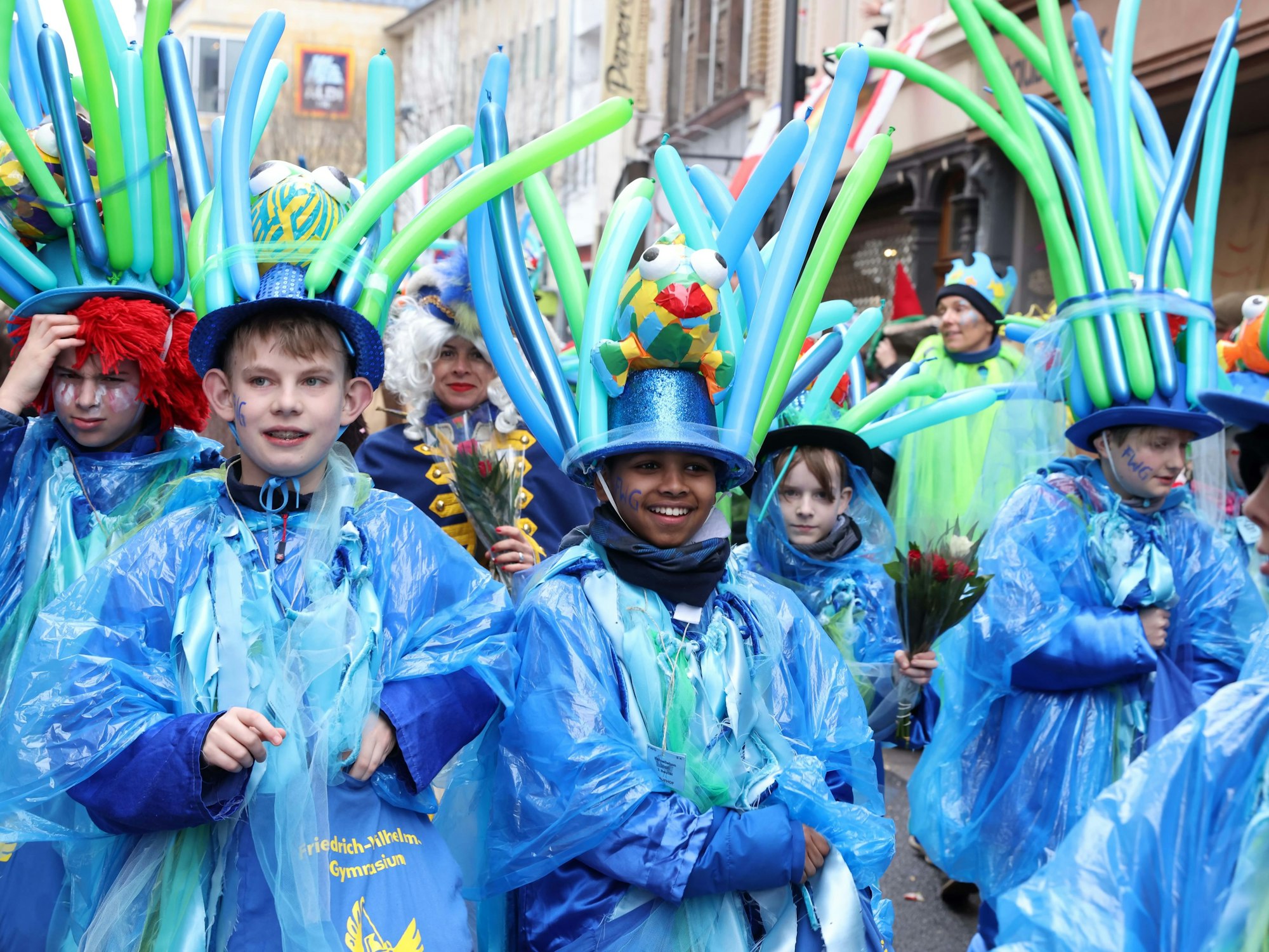 Schülerinnen und Schüler in regenfesten Karnevalskostümen.