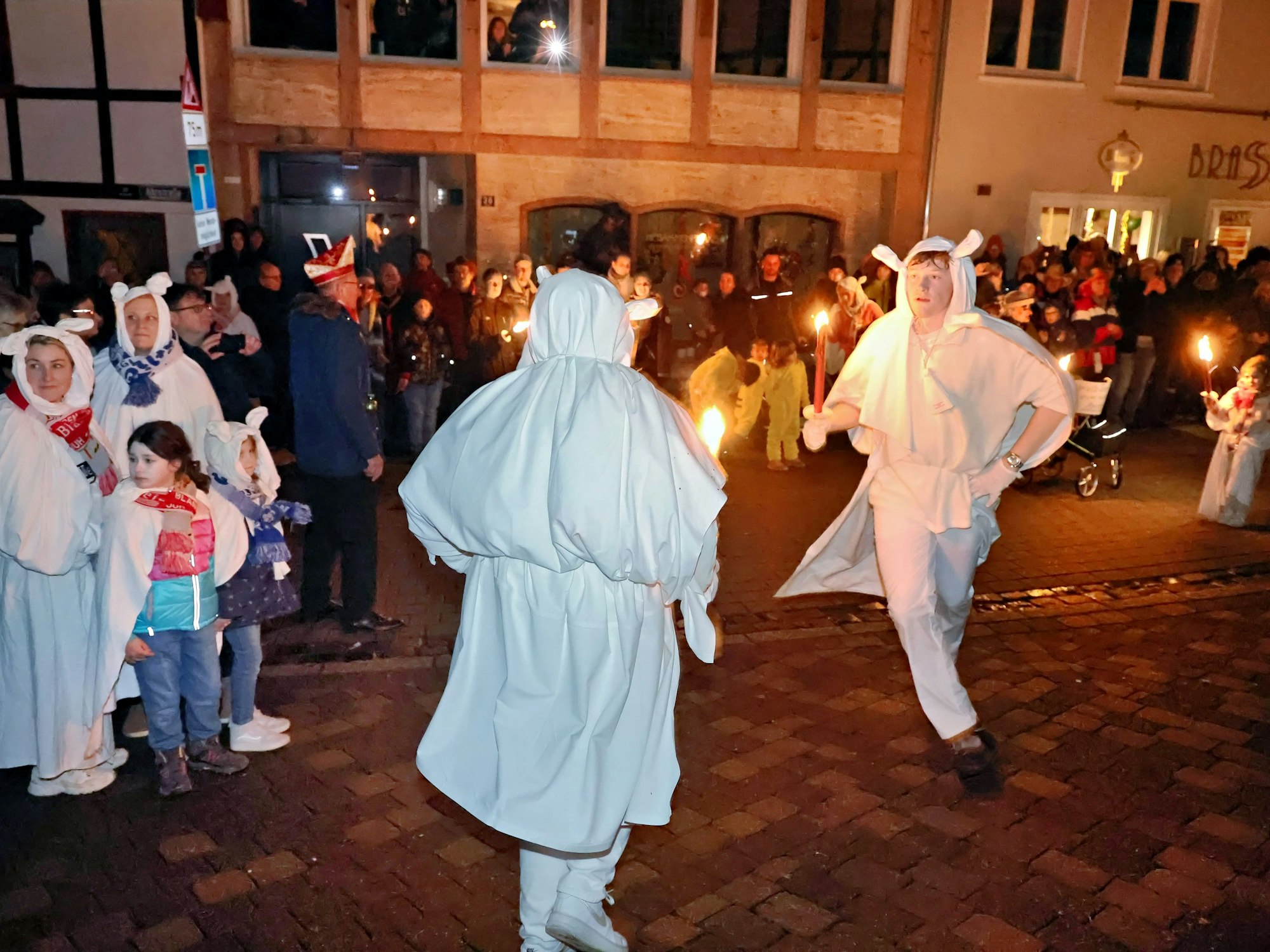 Die Jecken Böhnchen sind Traditionsfiguren im Blankenheimer Karneval. Dem Geisterzug springen sie voran und tanzen. Einige Zuschauer beobachten die beiden als Geister verkleideten jungen Männer.
