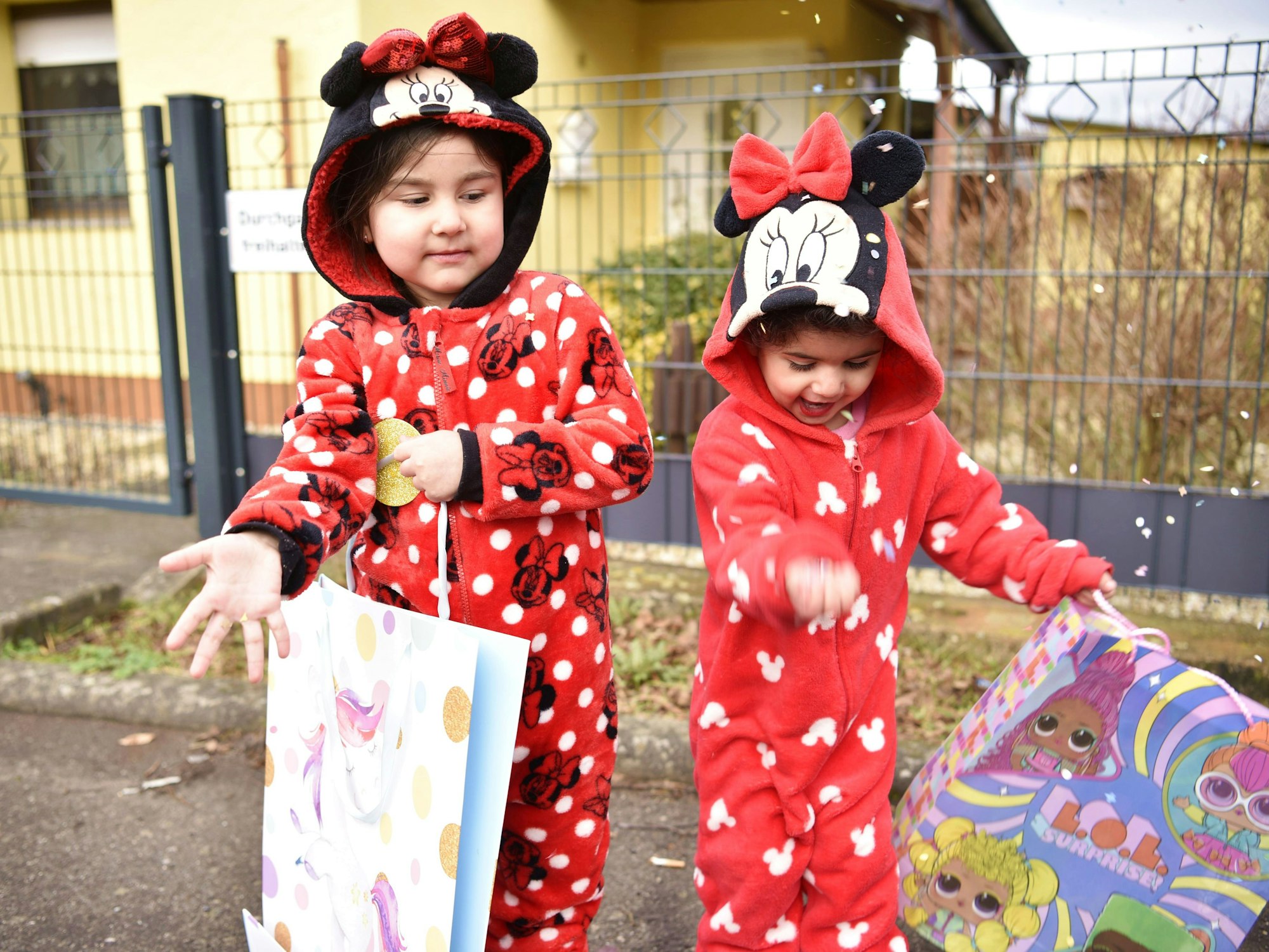 Larissa und Armanda aus Schleiden stehen als Mini-Mäuse verkleidet am Straßenrand und werfen Kamelle.