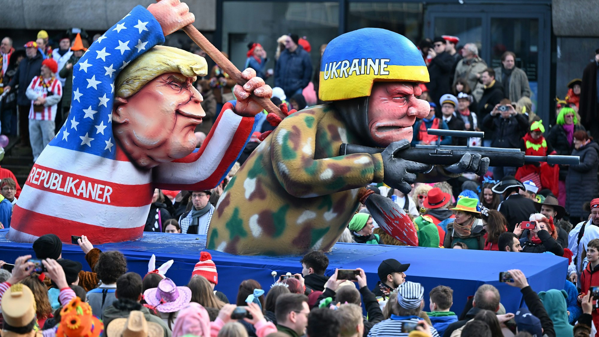 Düsseldorfer Mottowagen, auf dem Ex-US-Präsident Donald Tromp einen ukrainischen Soldaten mit einem Speer durchbohrt