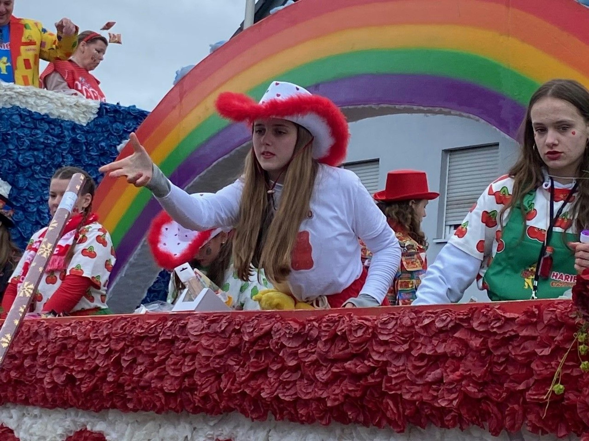 Auf dem Bild sind Mädchen zu sehen, die etwas von einem Karnevalswagen werden.