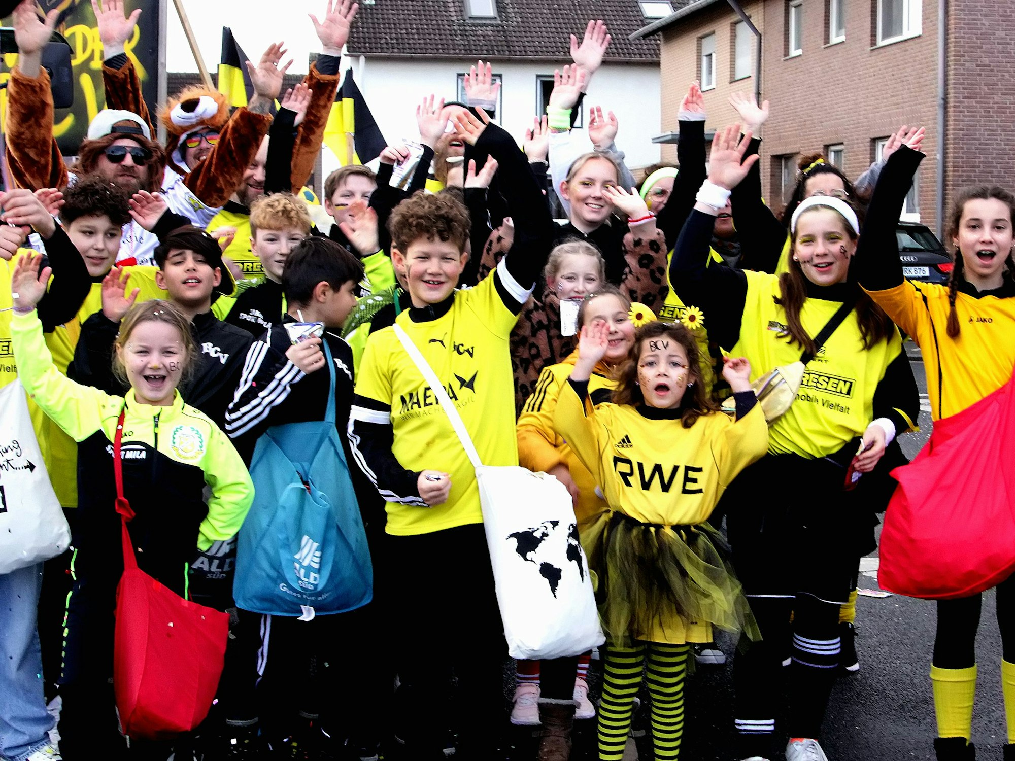 Kinder in gelben Trikots nehmen an einem Karnevalszug teil.