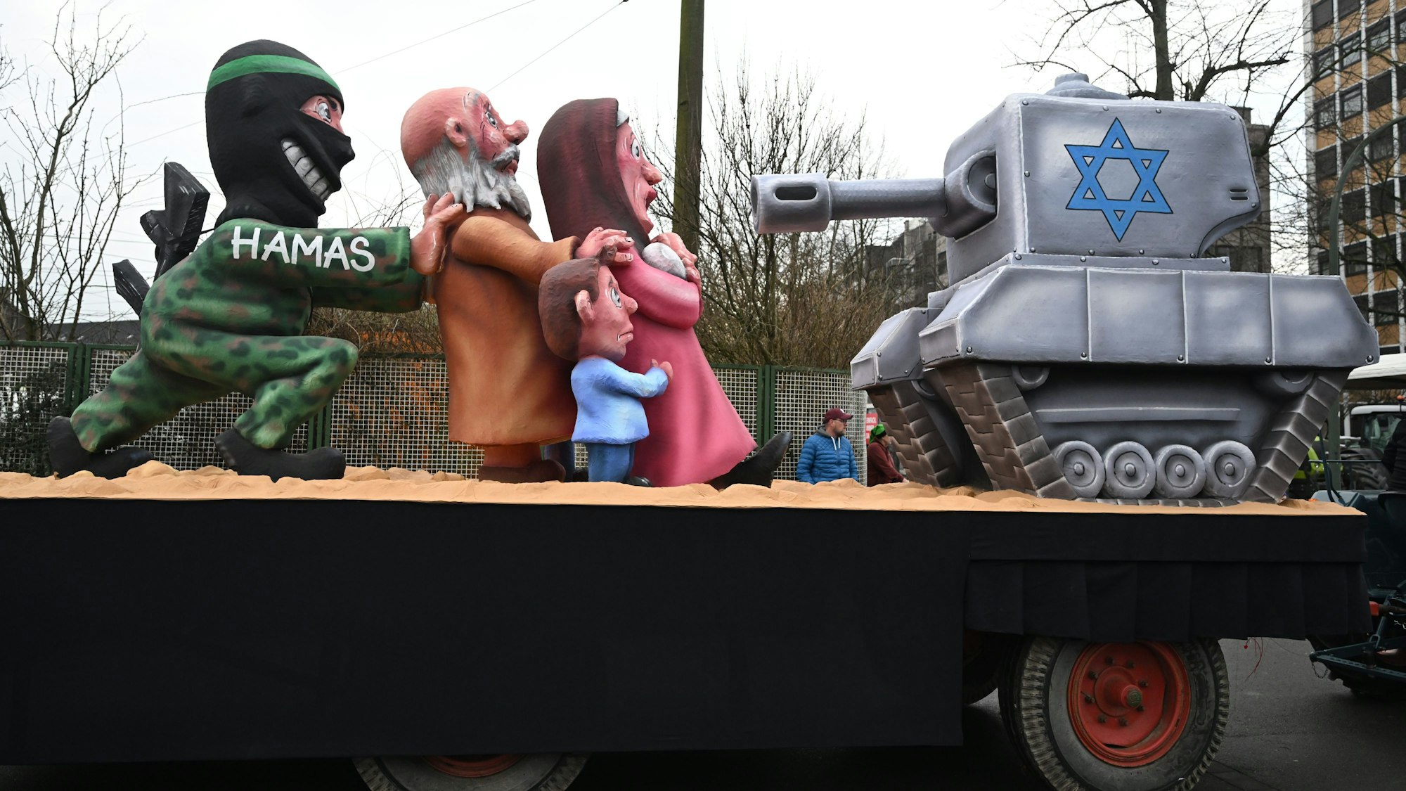 Persiflagewagen beim Rosenmontagszug 2024 in Düsseldorf: Der Nahostkrieg ist ebenfalls Thema, die Hamas-Terroristen schieben Zivilisten an die Kriegsfront.