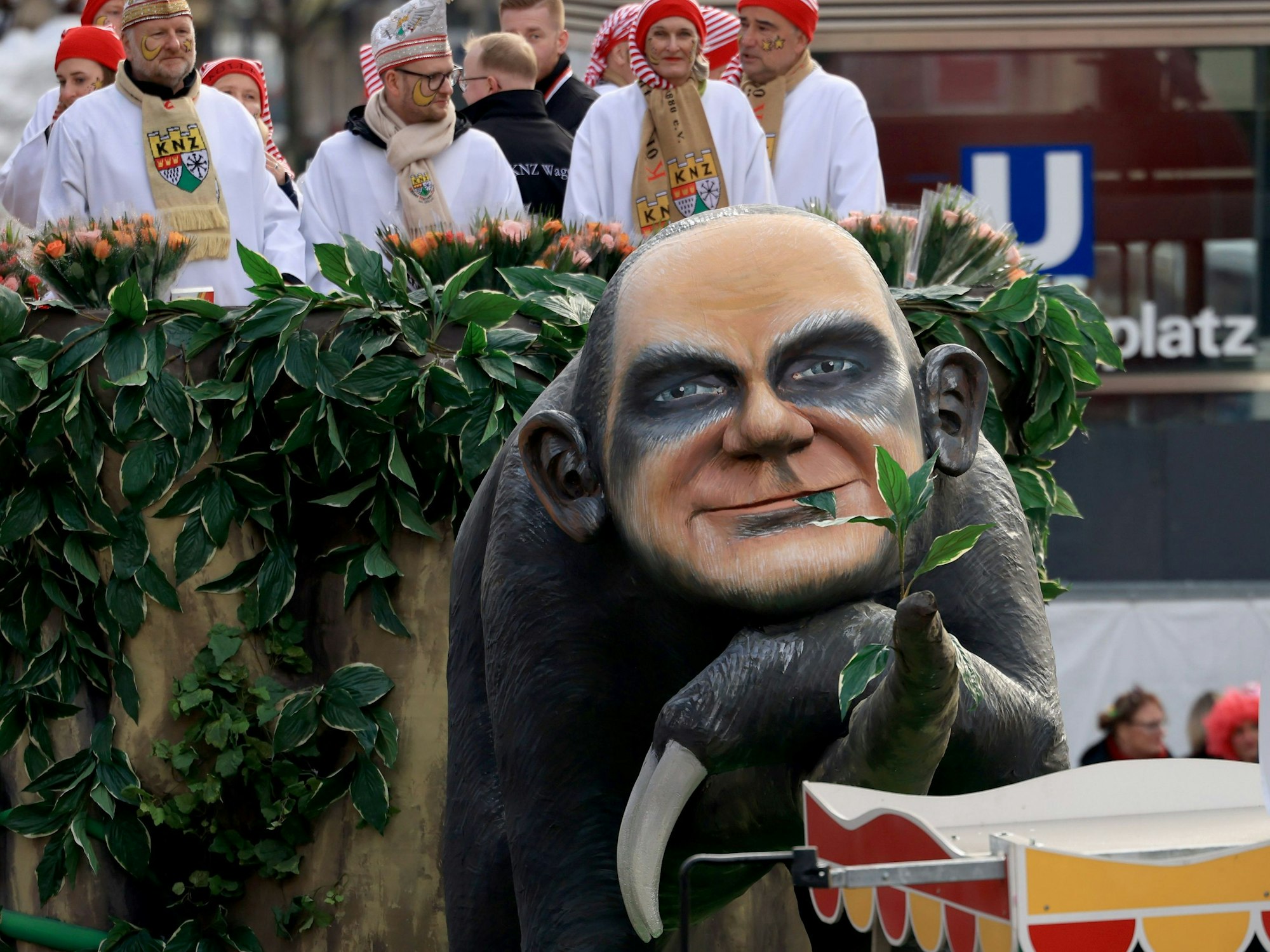 Ein Karnevalswagen ziert ein Faultier, das das Gesicht von Bundeskanzler Olaf Scholz hat.