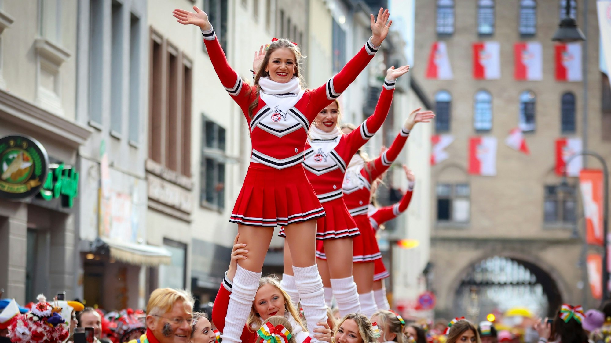 Auch die Cheerleader des 1. FC Köln sind beim Zug dabei. Hier werden einige Tänzerinnen auf Händen durch die Straße getragen.