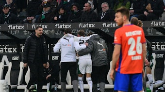 Ein Spieler von Borussia Mönchengladbach wird mithilfe von zwei Medizinern nach einer Verletzung vom Platz geführt.