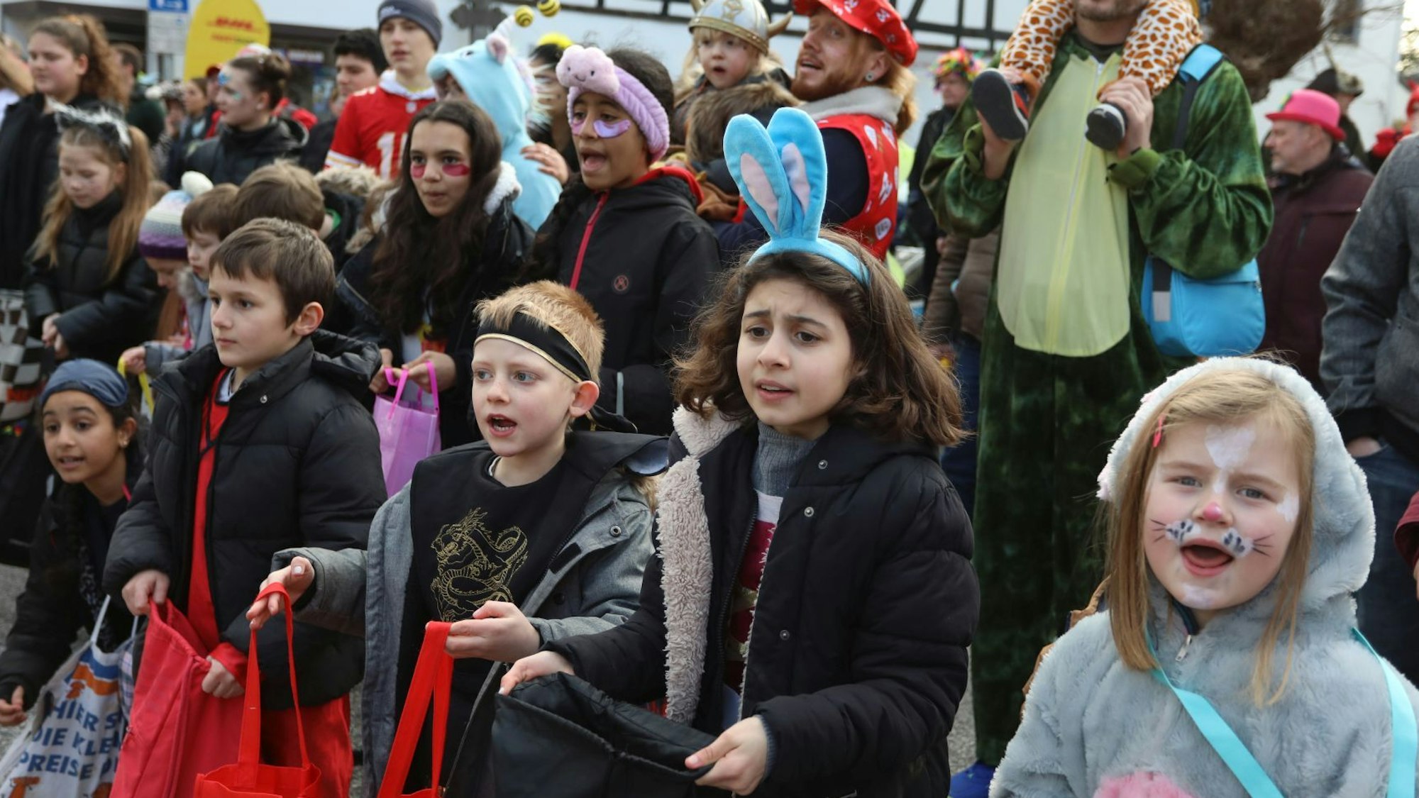 Kostümierte Kinder mit Stofftaschen in den Händen hoffen auf Kamelle.