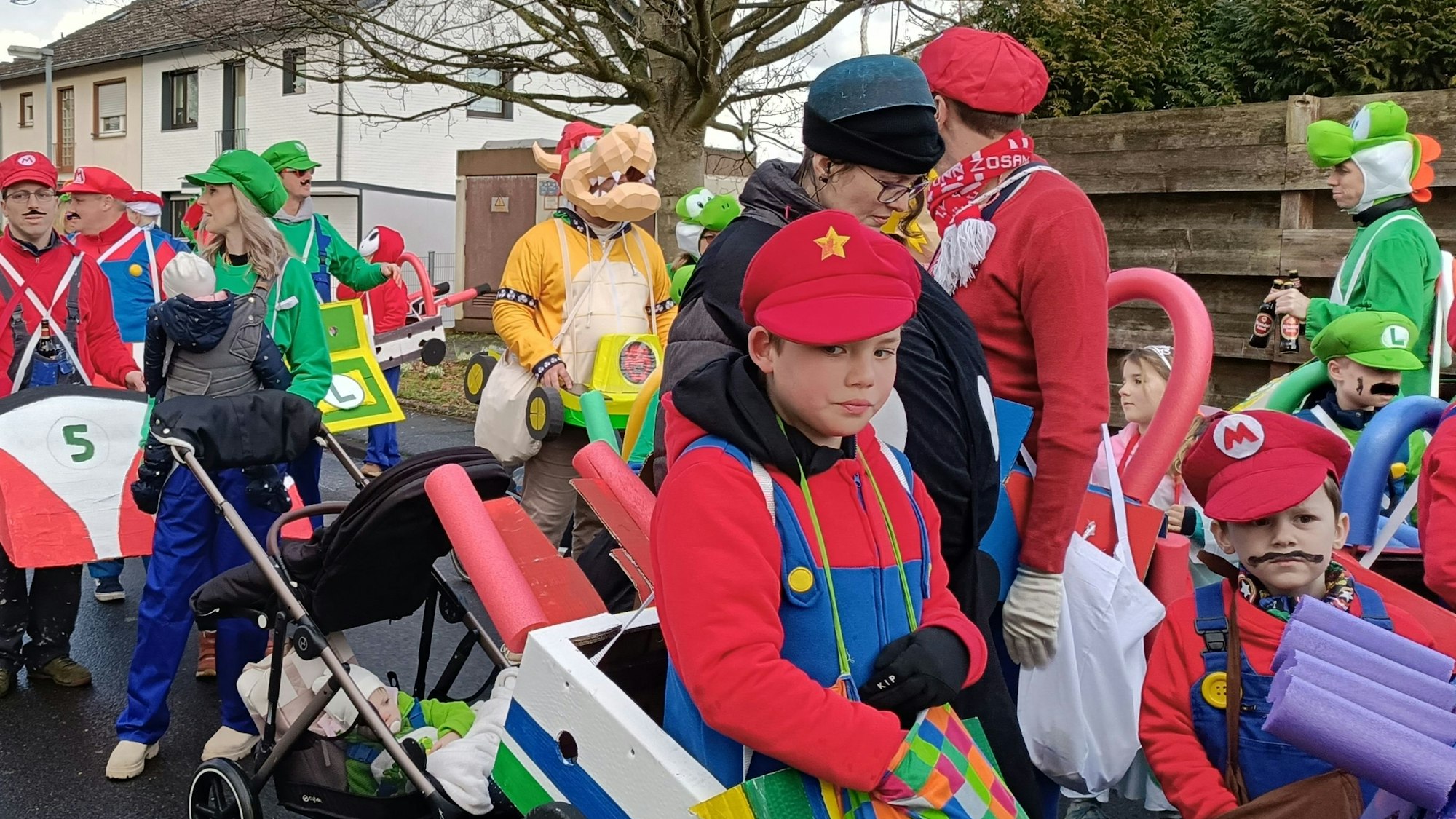 Teilnehmer eines Karnevalszugs in bunten Super-Mario-Kostümen.