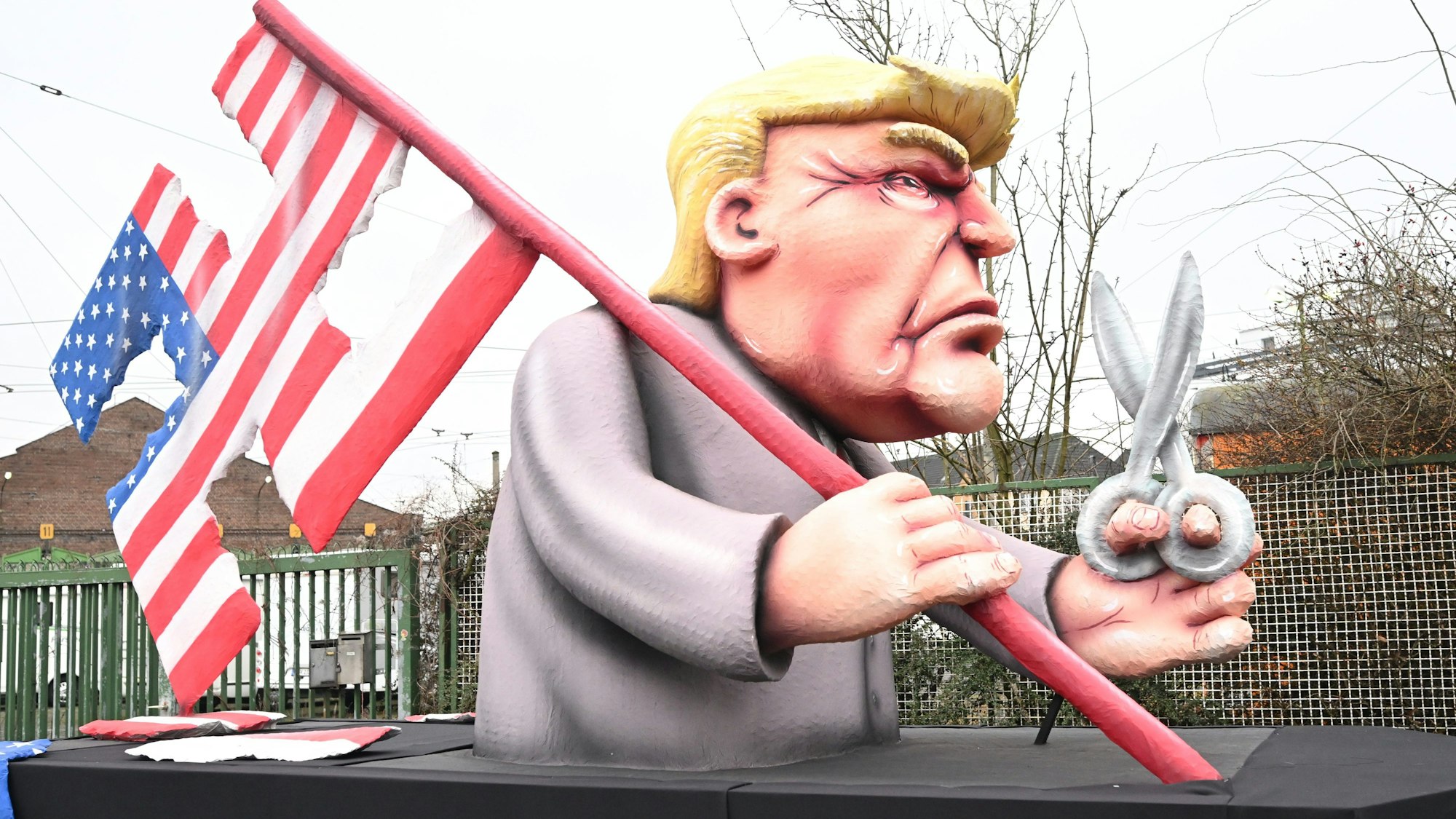 Persiflagewagen beim Rosenmontagszug 2024 in Düsseldorf: Donald Trump schneidet die amerikanische Flagge zum Hakenkreuz-Motiv.