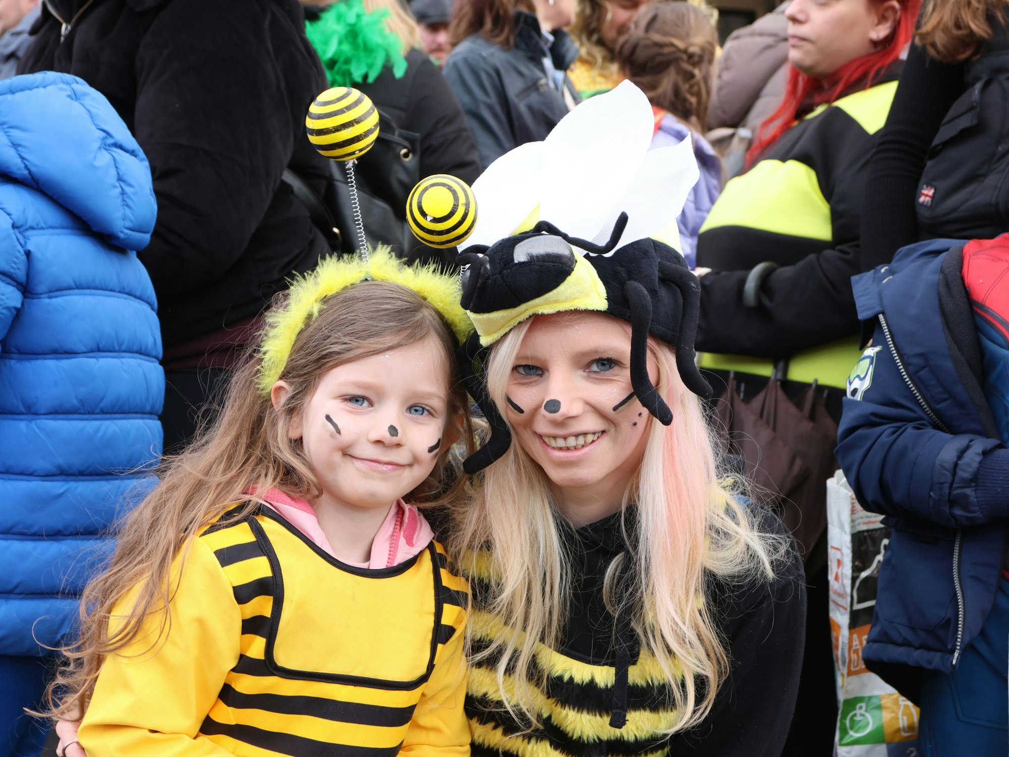 Eine Mutter und ihre Tochter bei einem Karnevalsumzug. Beide sind als Biene verkleidet.