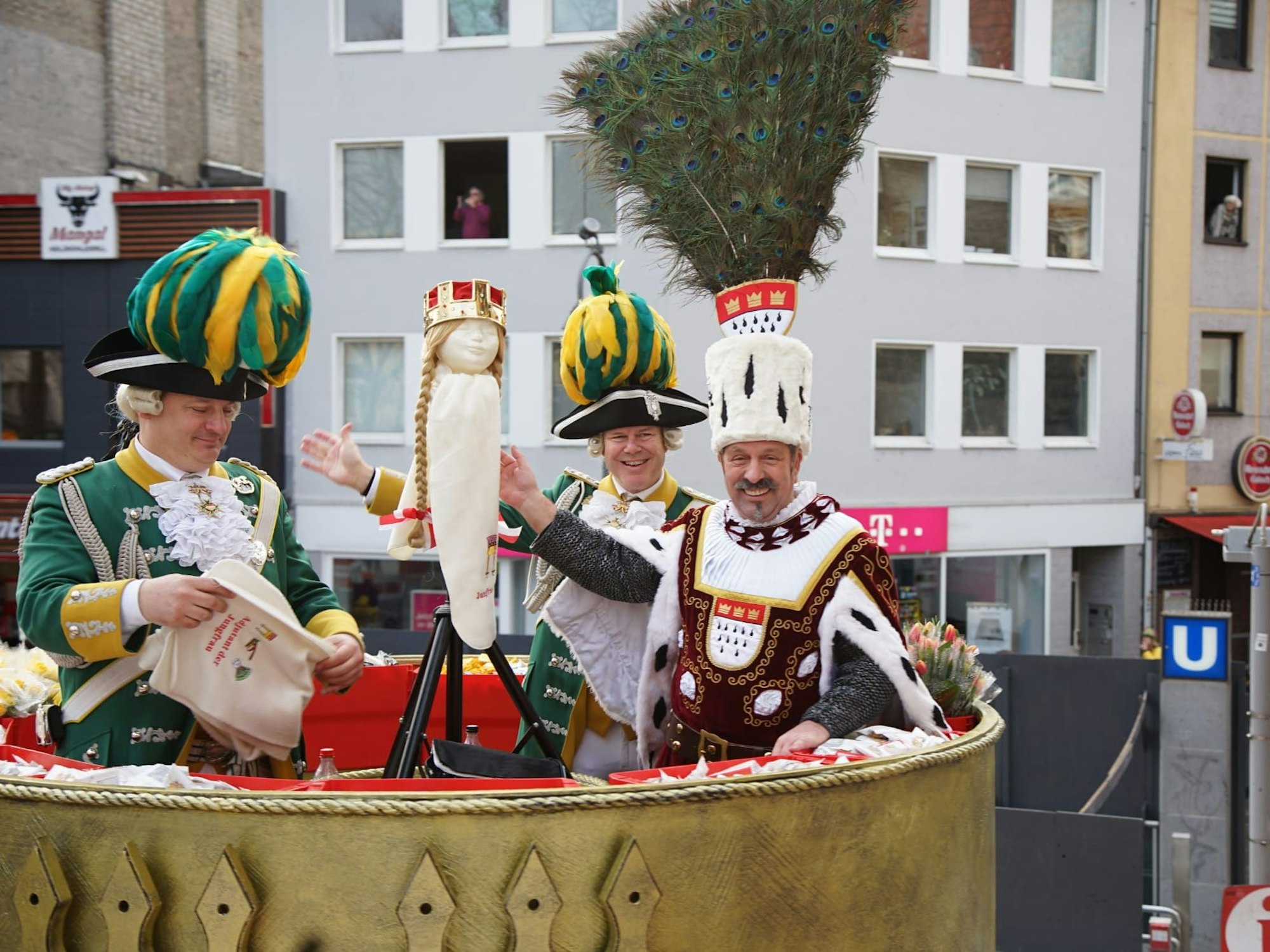 Auf einem Karnevalswagen präsentiert Bauer Werner eine Puppe, die Krone und Perücke der Jungfrau trägt.