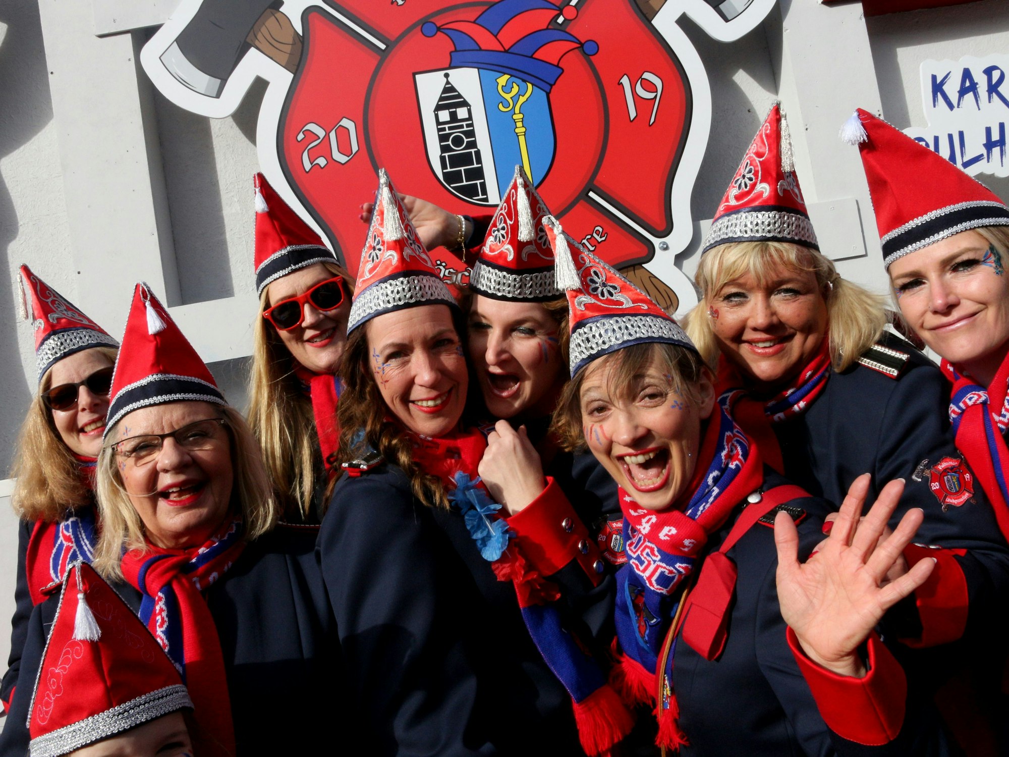 Die Frauen der KG Pulheimer Löschgrenadiere in ihren Uniformen in Blau und Rot lächeln in die Kamera.