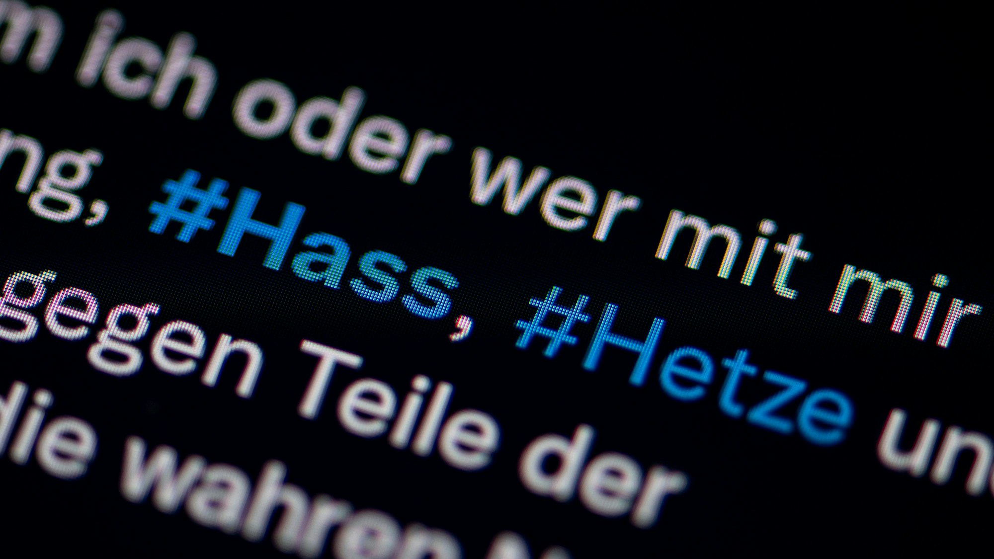 Auf dem Bildschirm eines Smartphones sieht man die Hashtags Hass und Hetze in einem Twitter-Post (heute X).
