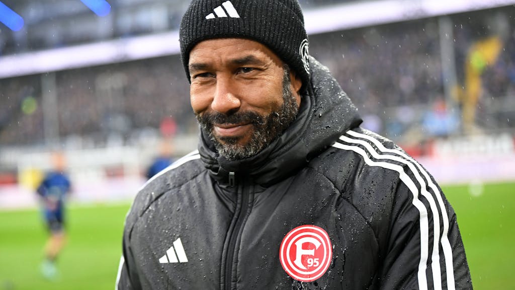 Fortuna Düsseldorfs Cheftrainer Daniel Thioune steht beim Auswärtsspiel beim SC paderborn im Stadion und lächelt.