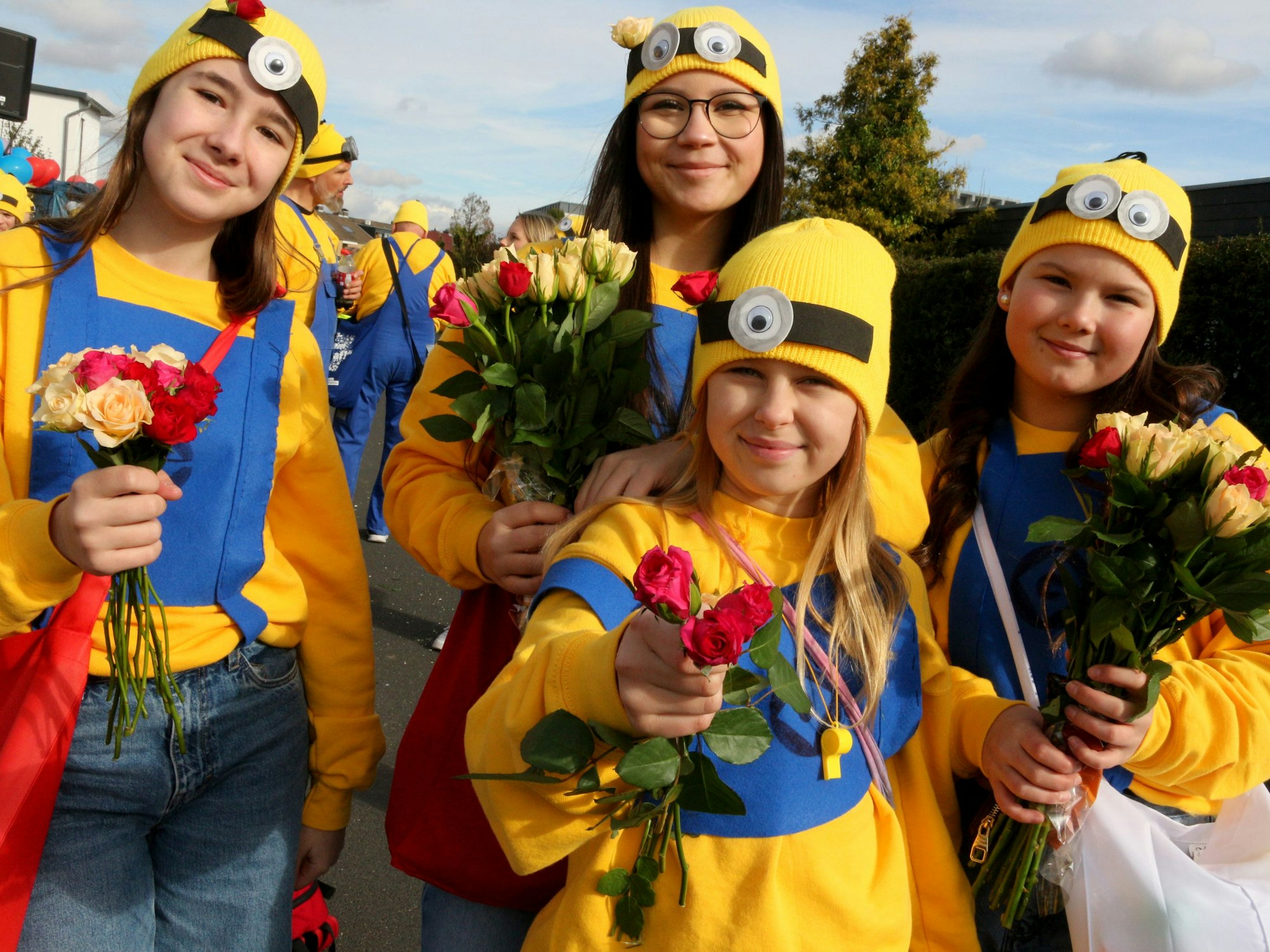 Vier Schülerinnen in Gelb-Blauen Kostümen verteilen kleine Blumensträuße.