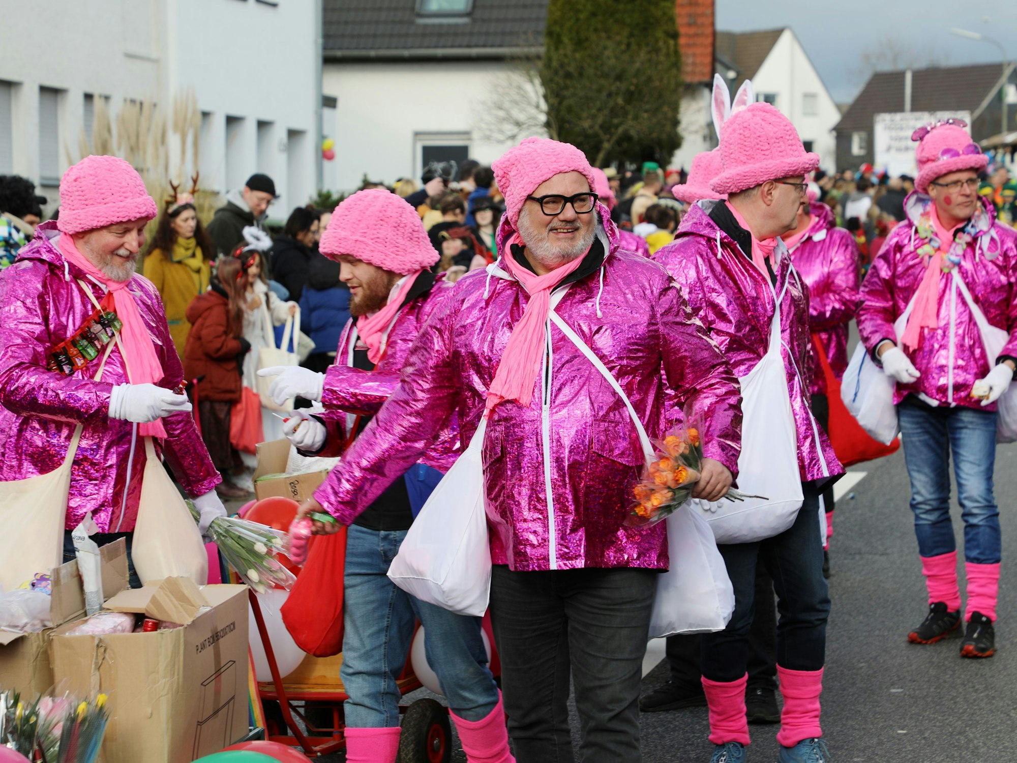 Pink gekleidete Männer gehen im Karnevalszug mit.