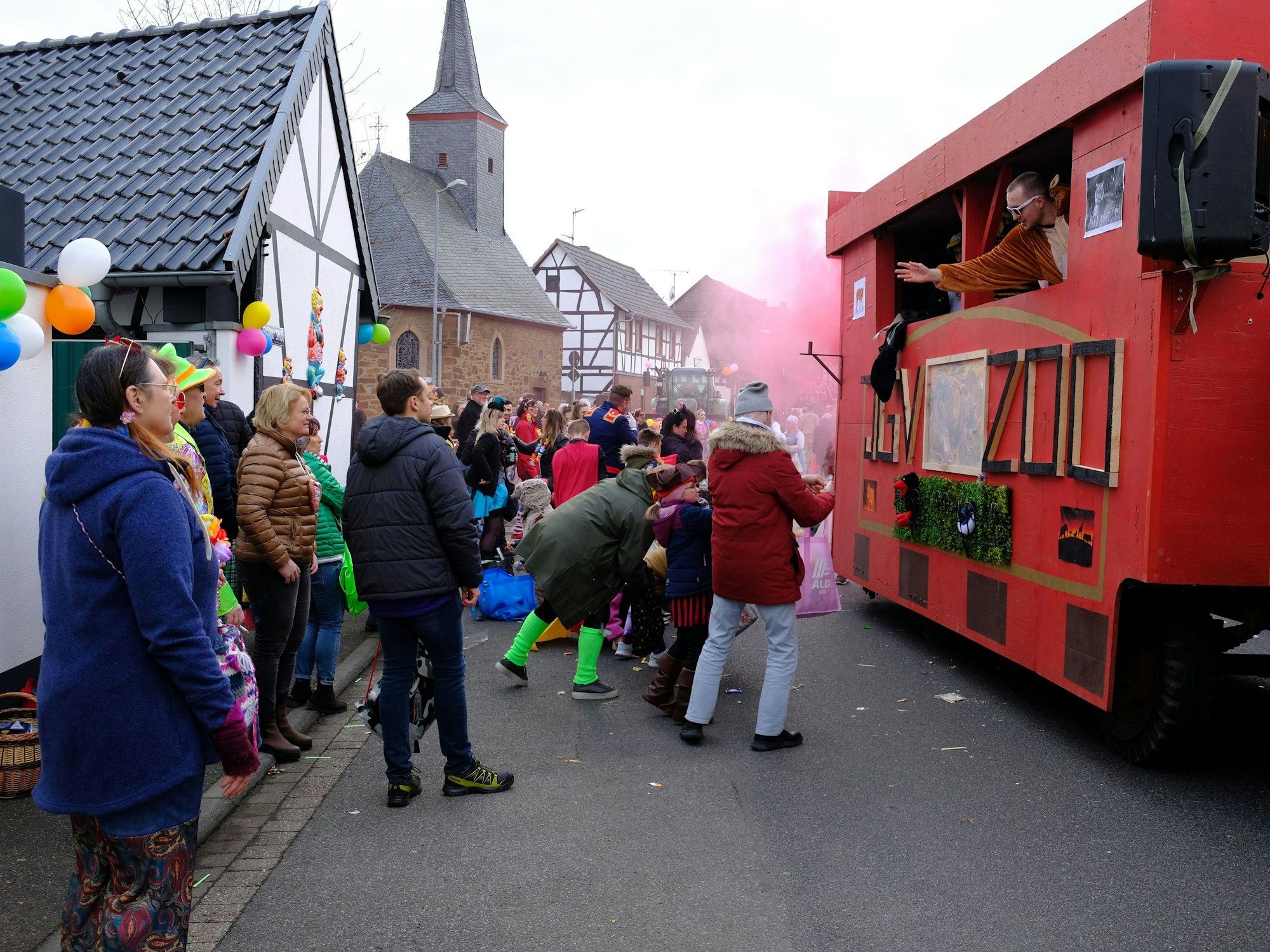 Viele Besucher kamen zum Abschluss des Straßenkarnevals zum Veilchendienstagszug nach Firmenich-Obergartzem. Zu sehen ist der Wagen des Junggesellenvereins. rosa Nebel steigt aus dem hinteren Teil auf.