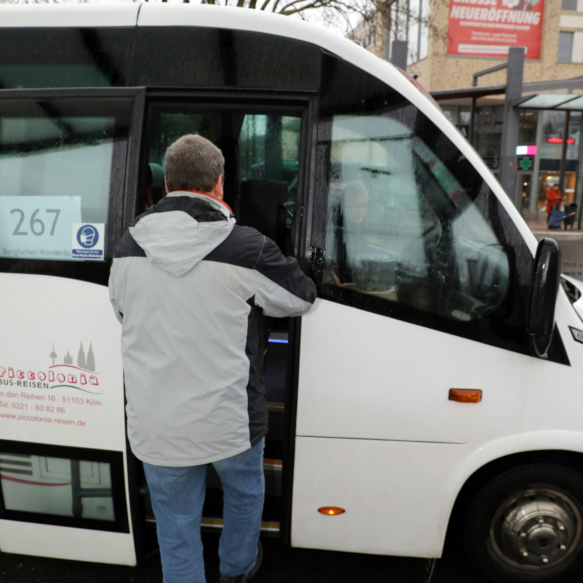 Ein Fahrgast betritt den weiß gehaltenen Wanderbus.