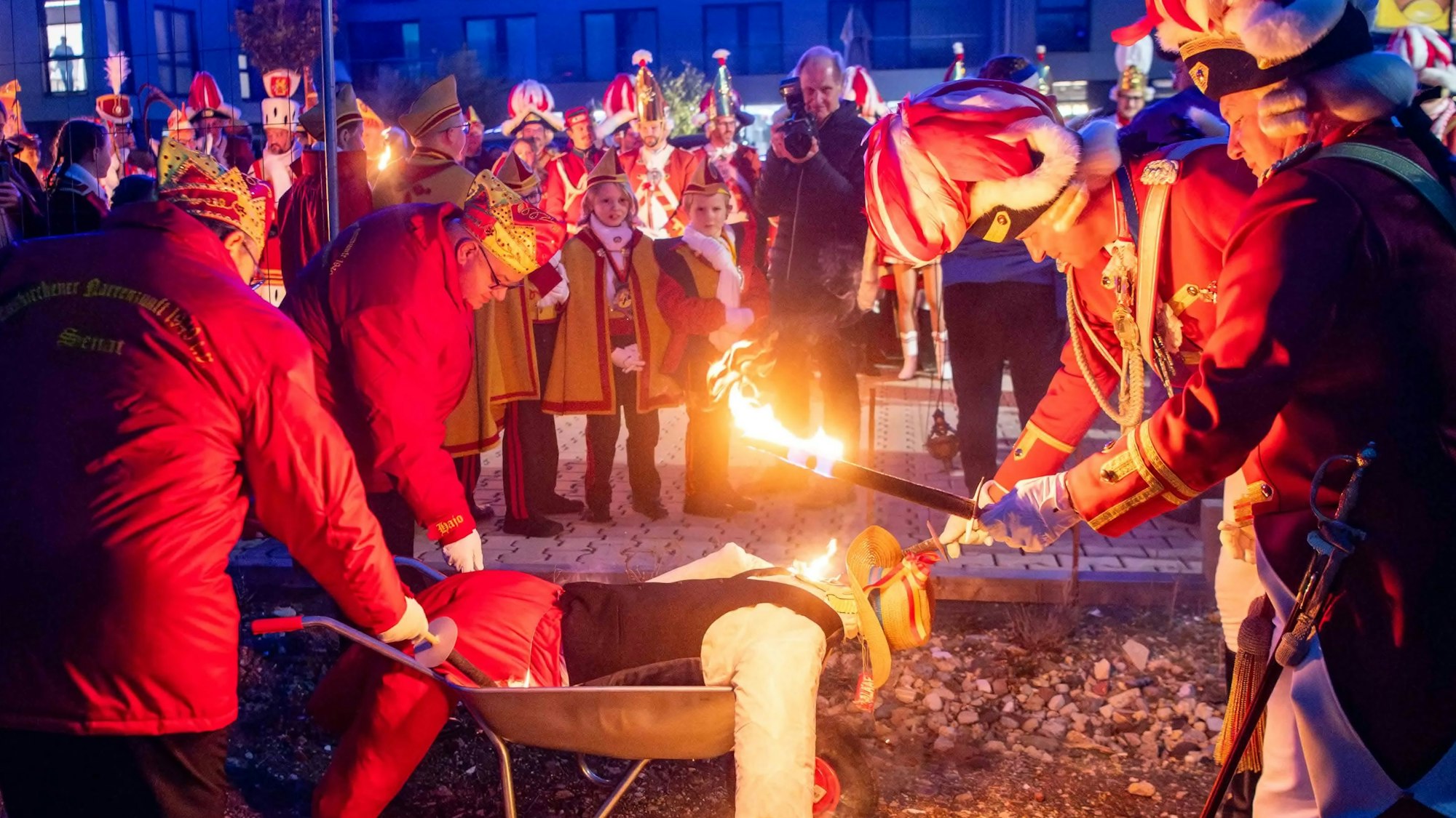 Die Männer der Euskirchener Karnevalsgesellschaft zünden mit einer brennenden Fackel den Nubbel – eine bekleidete Strohpuppe – an, die in einer Schubkarre liegt.
